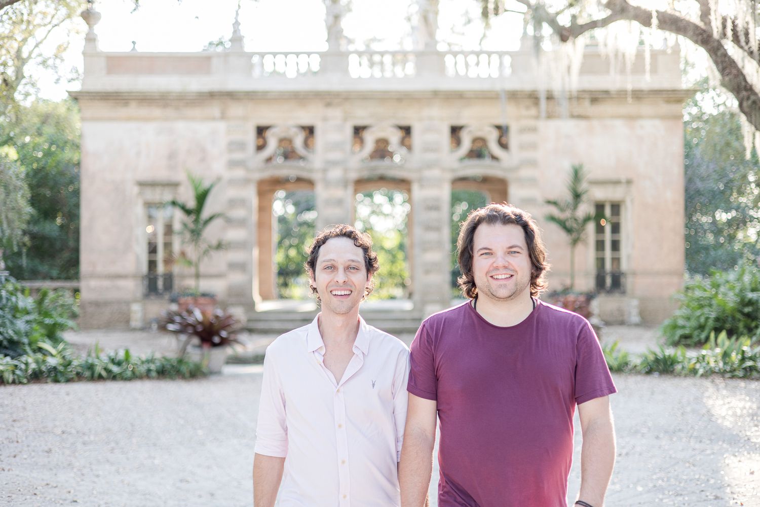 Two people stand together in front of an ornate garden structure.