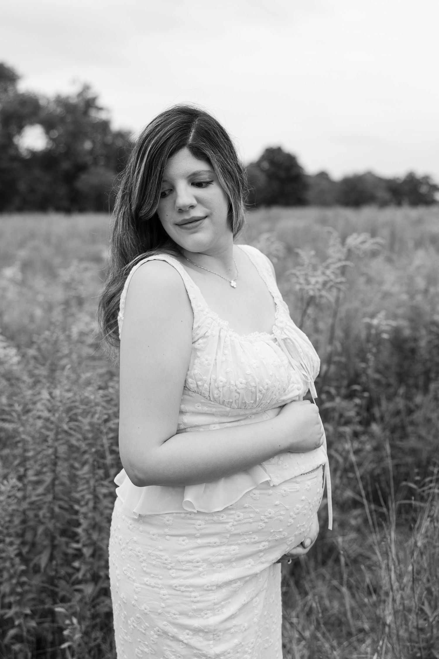 A joyful black and white maternity portrait in a natural field setting.