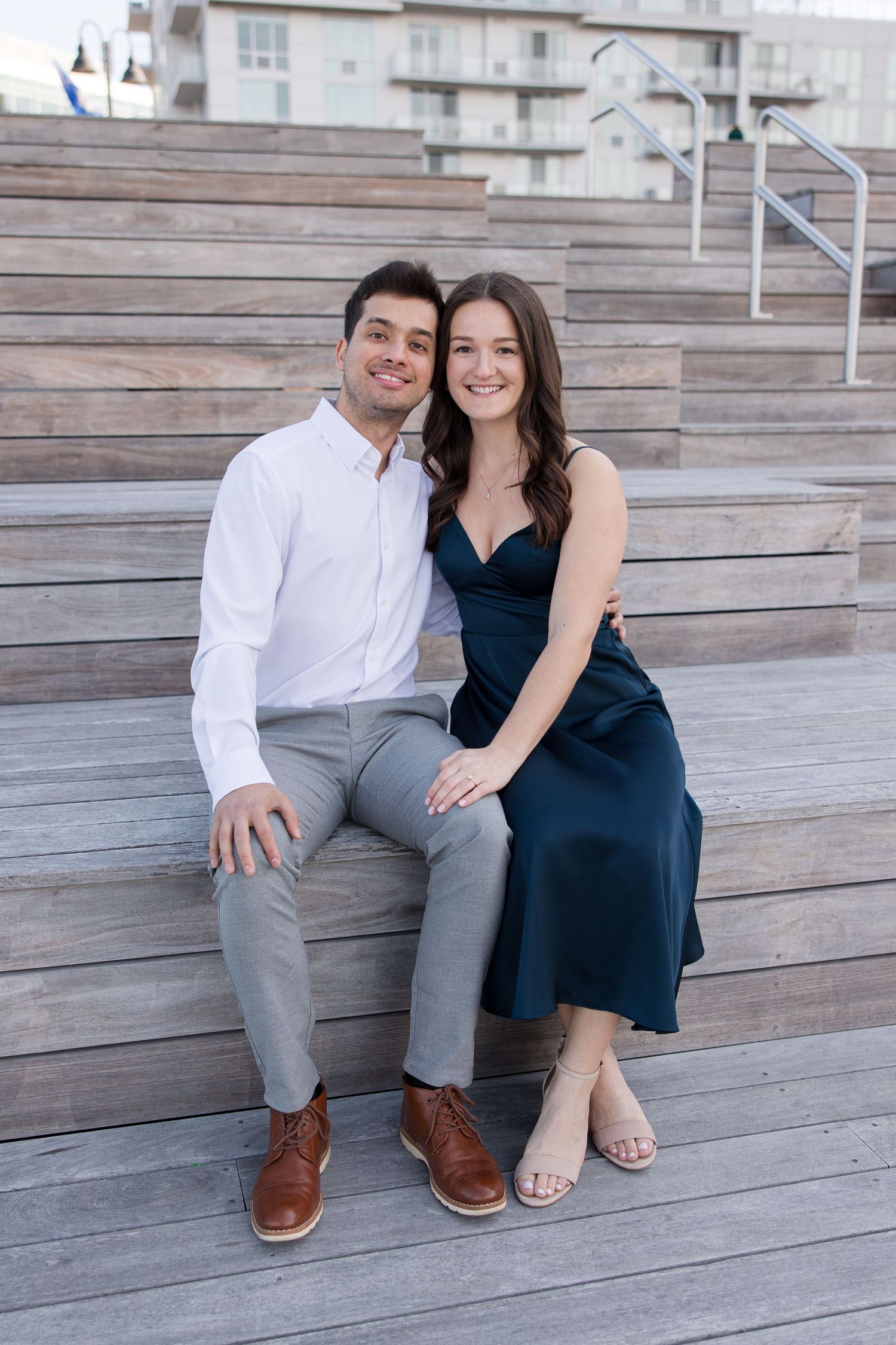 Couple sits together on wooden amphitheater steps during outdoor photoshoot.