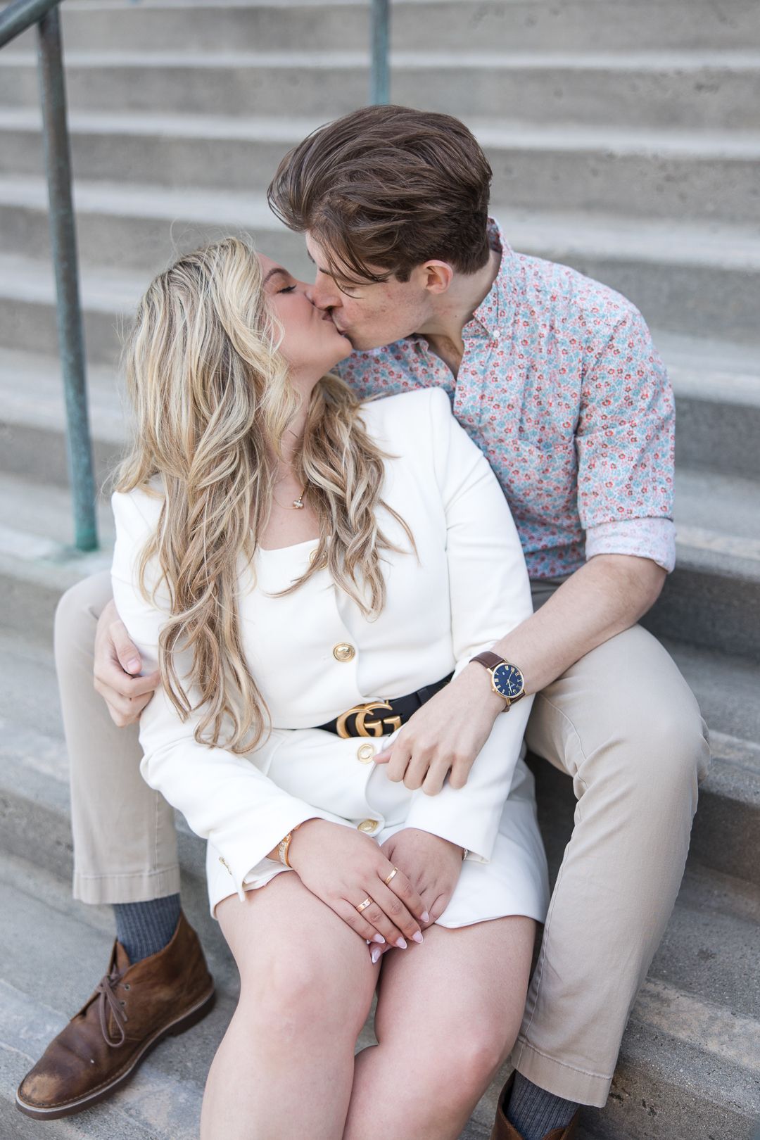 A romantic couple sharing a tender kiss while sitting together on stone steps.