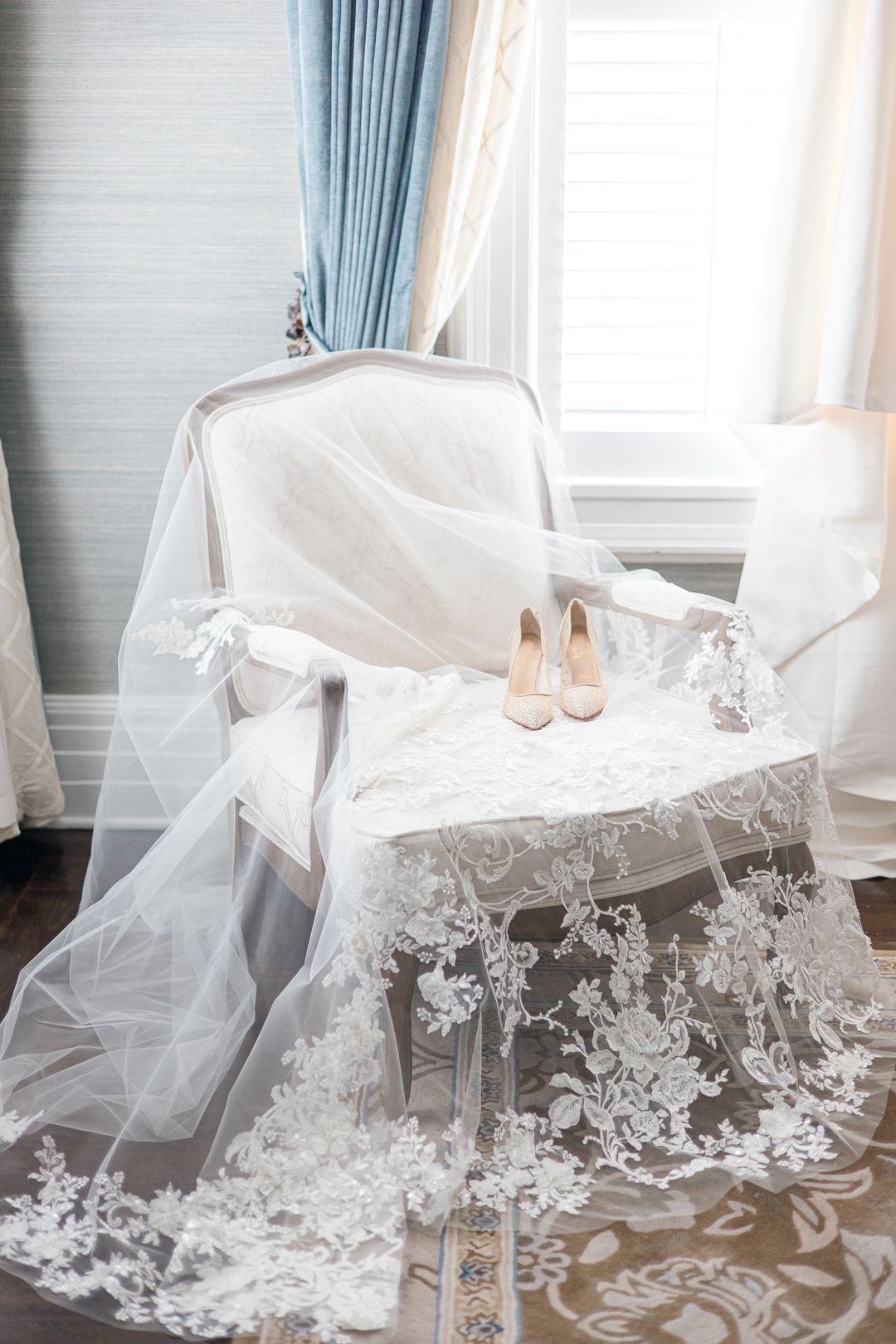 Wedding veil and shoes arranged on vintage chair with lace details.