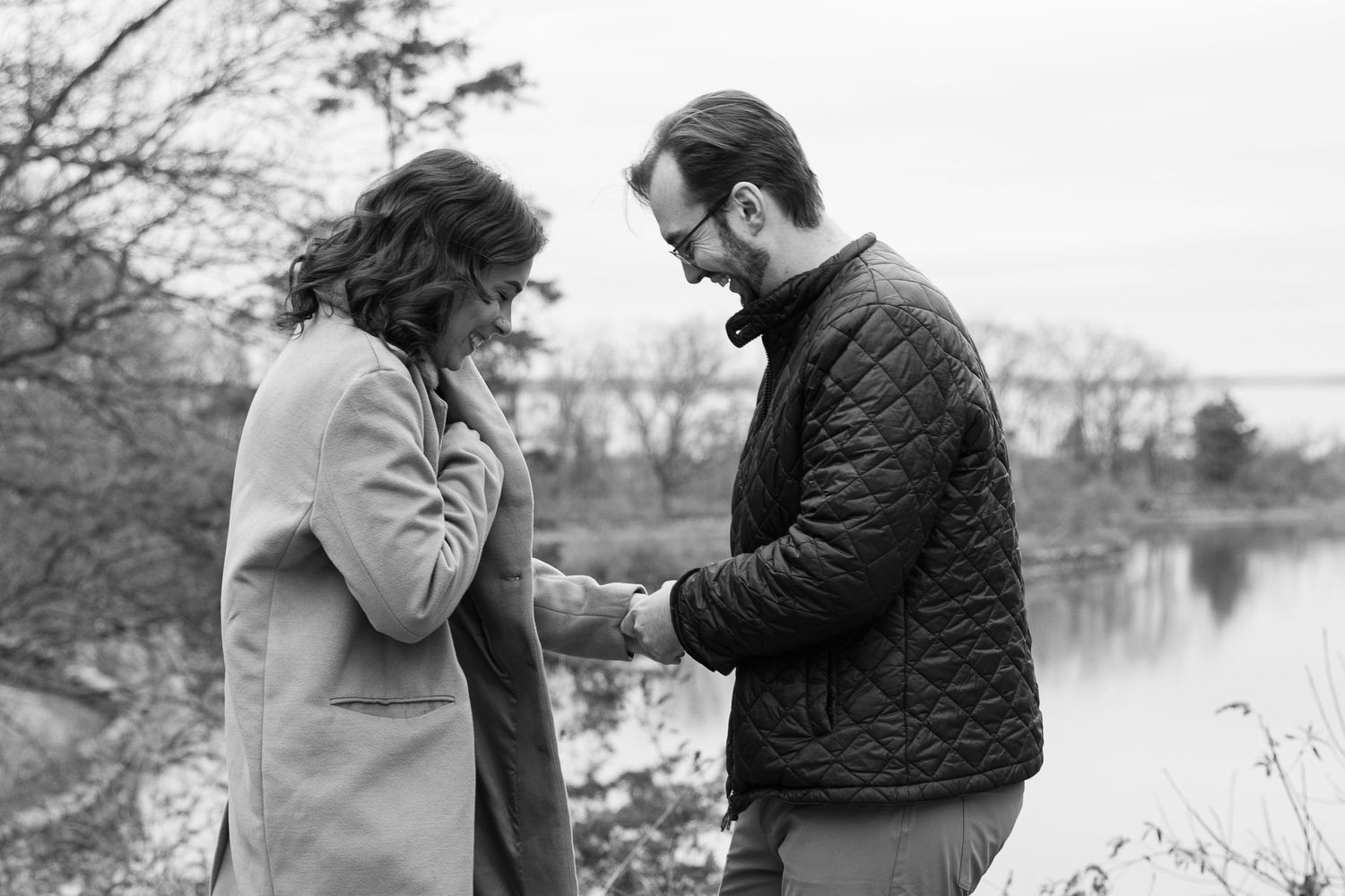 Black and white photo of couple sharing intimate moment by lakeside.