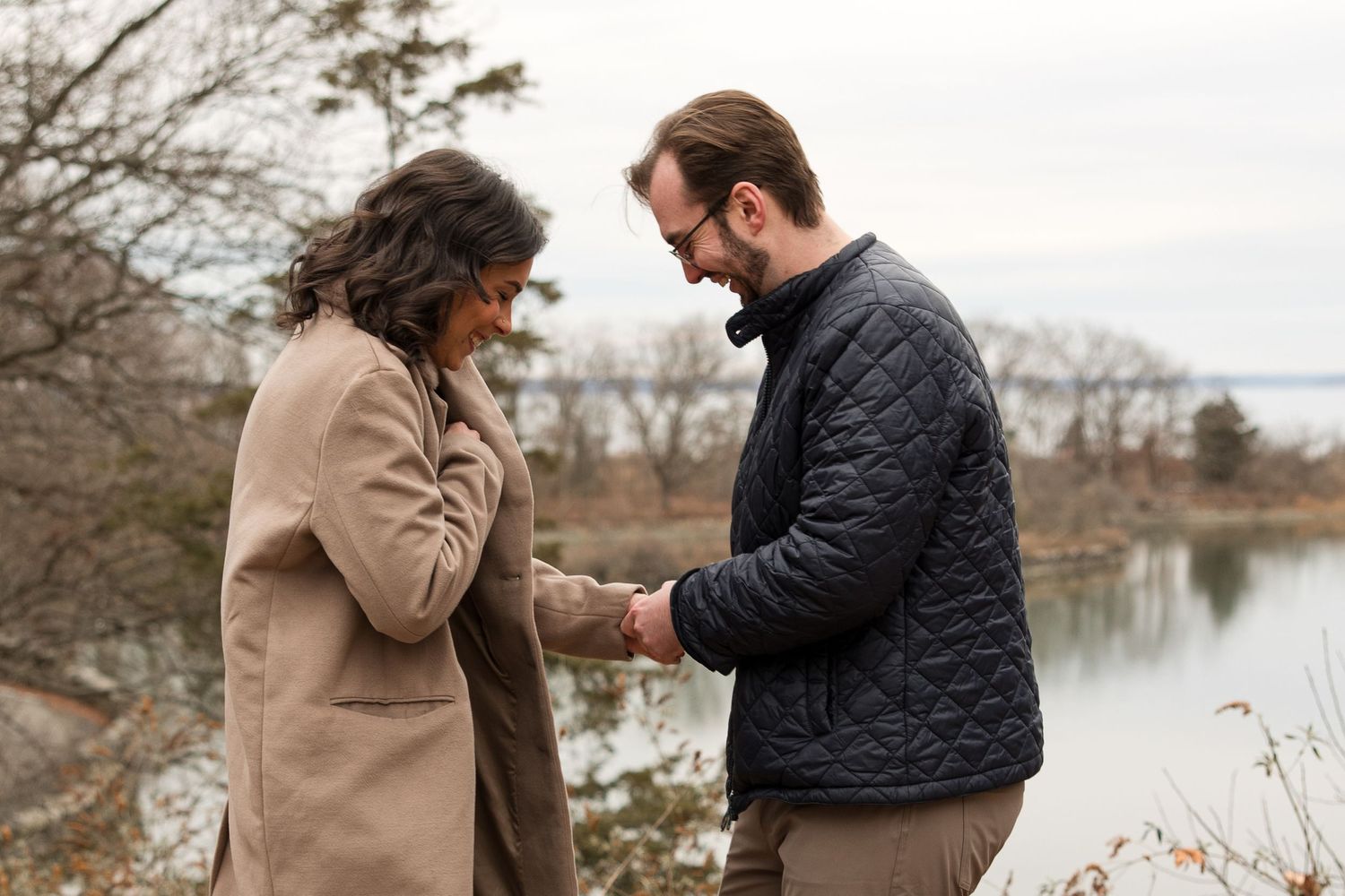 A couple shares an intimate moment while exchanging rings near a lake.