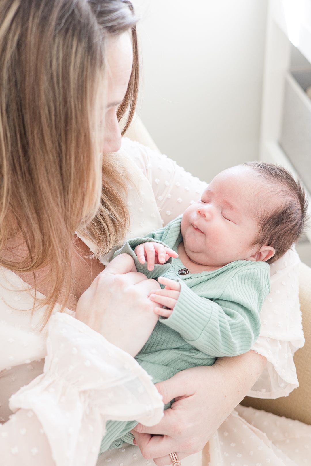 A peaceful moment with a sleeping newborn in mint green against soft white bedding.