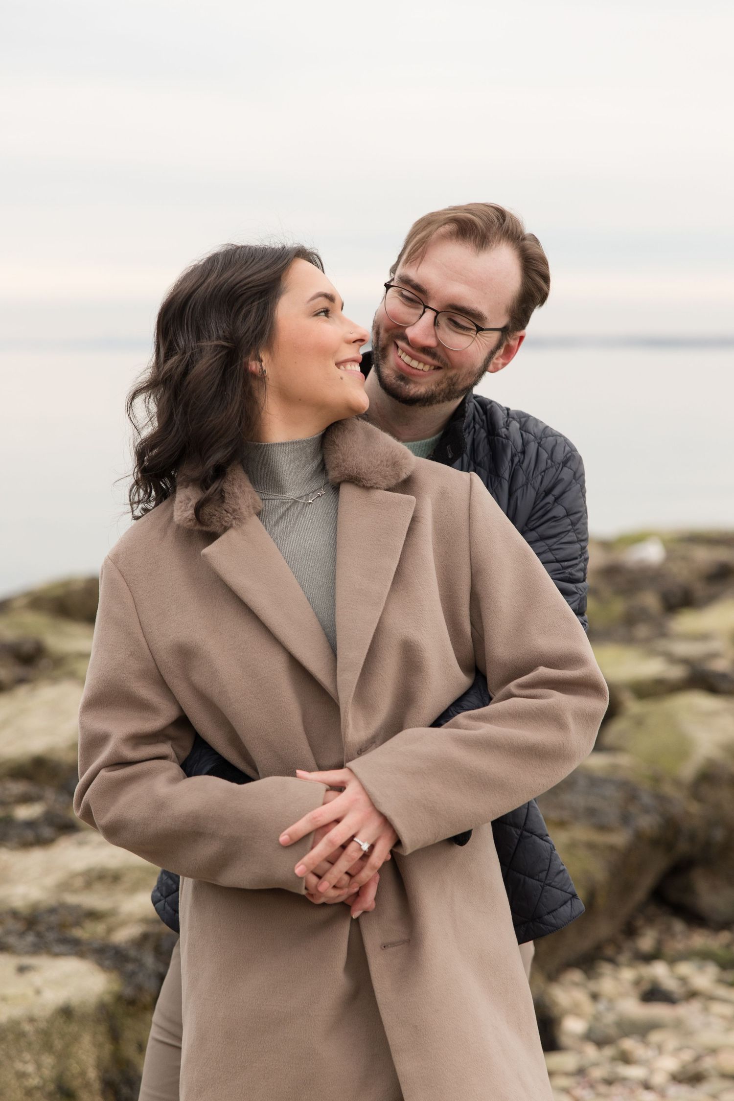 A couple sharing a joyful moment together on a rocky beach.
