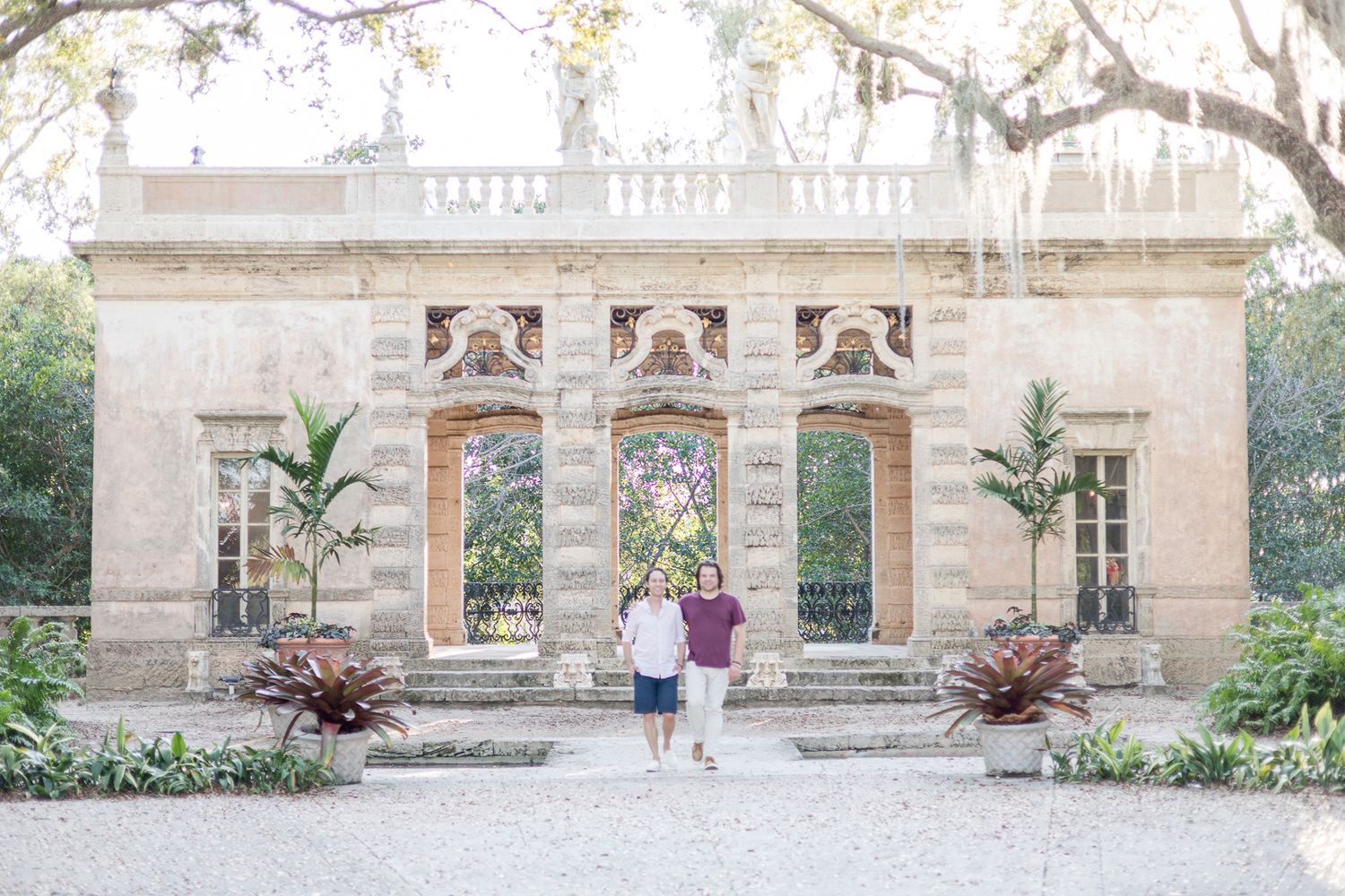 Historic stone mansion with ornate architectural details and tropical plants in the garden.