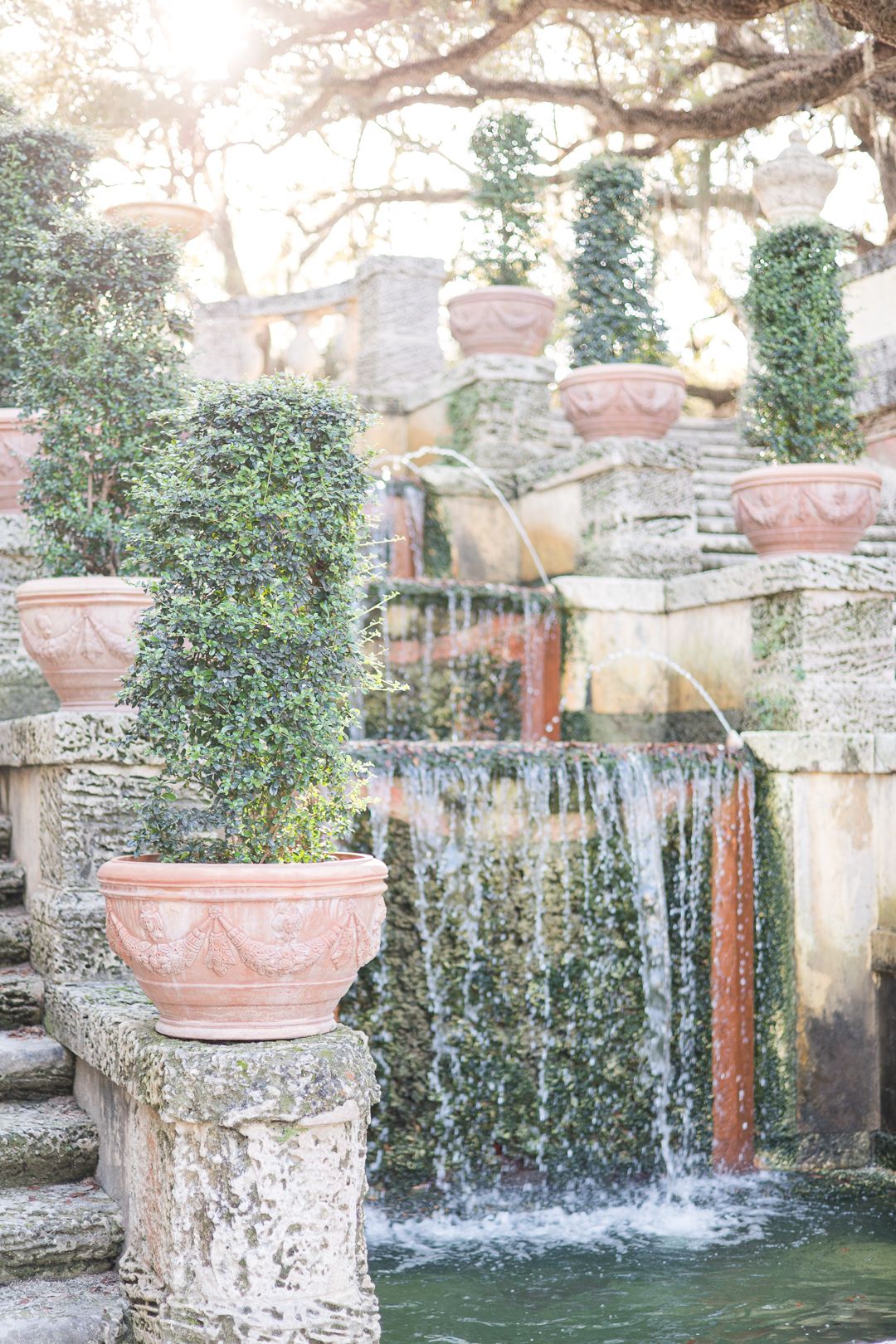Decorative garden waterfall with terracotta pots and climbing ivy in soft, dreamy lighting.