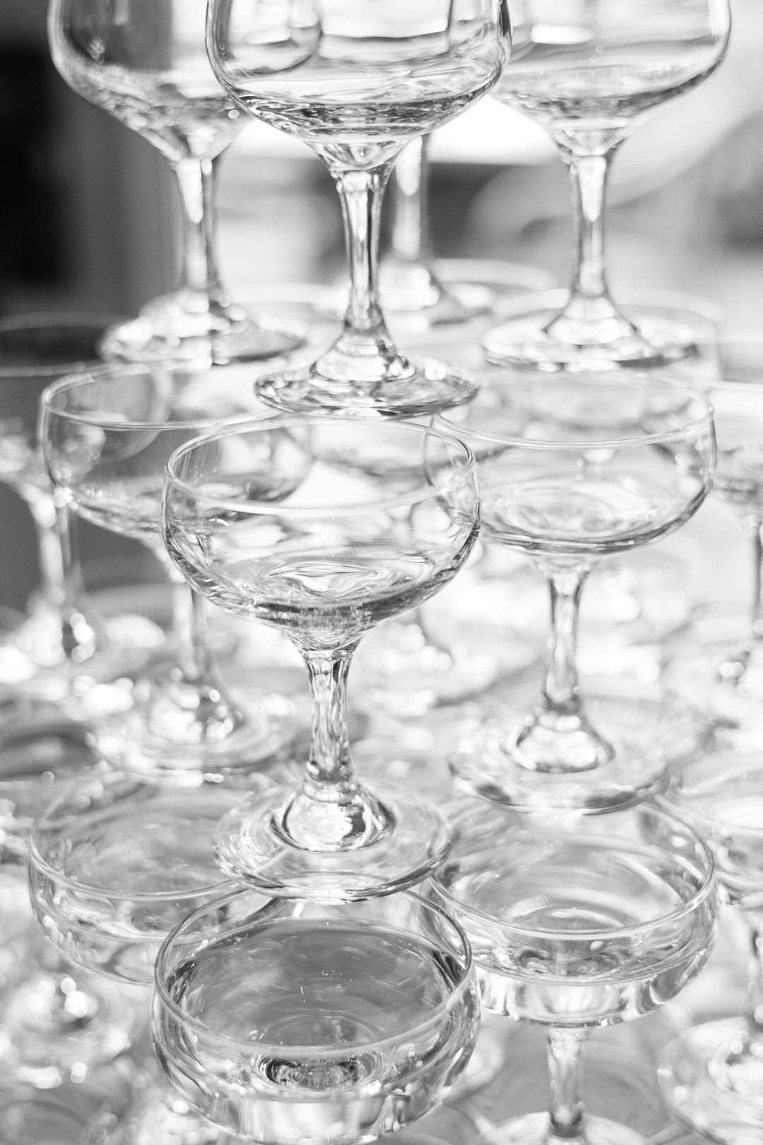 Stack of elegant coupe champagne glasses arranged in a tower formation.