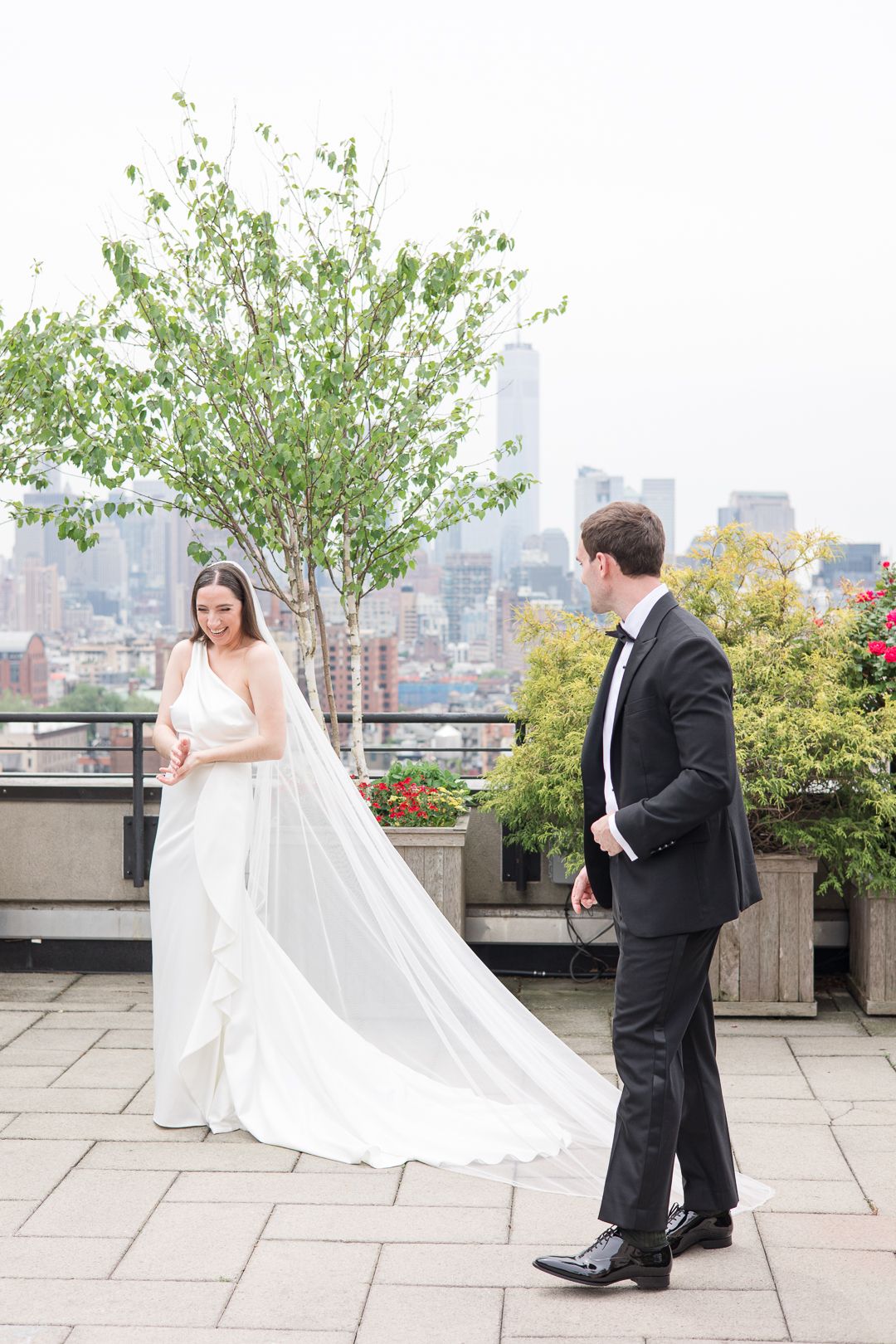 Candid wedding moment on a New York rooftop with Empire State Building visible in the distance.