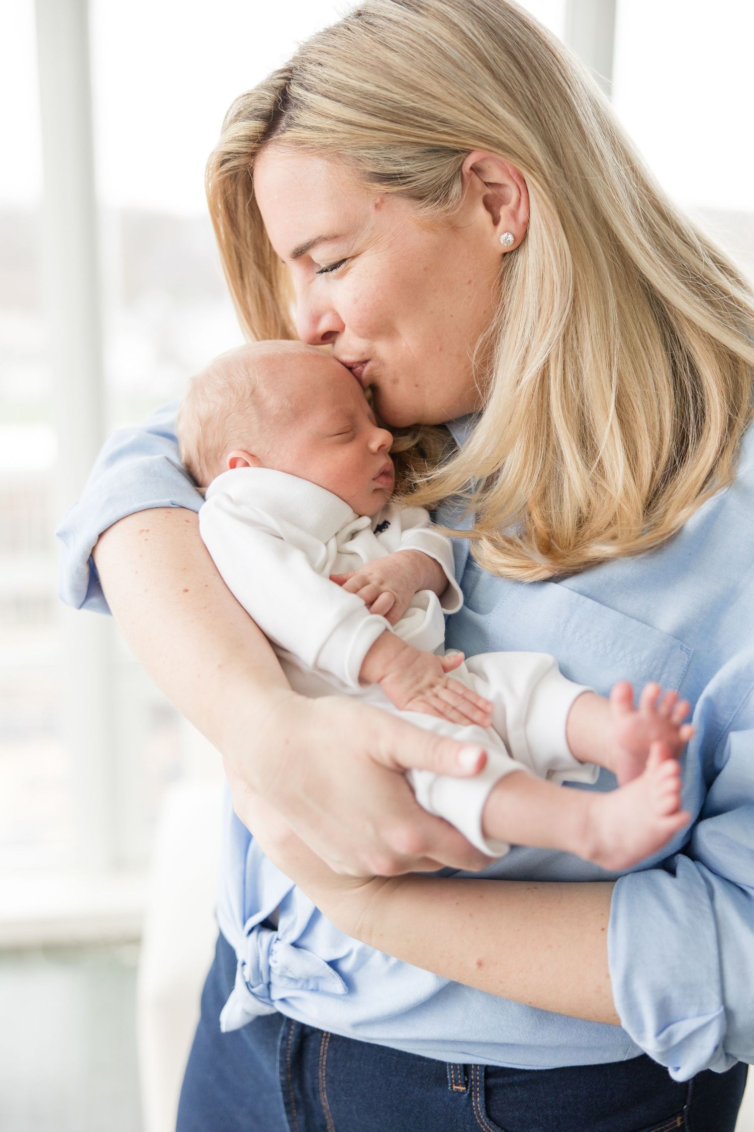 Harbor Point Newborn Photographer | Stamford Newborn Photography | A mom gently kissing their sleeping newborn baby.
