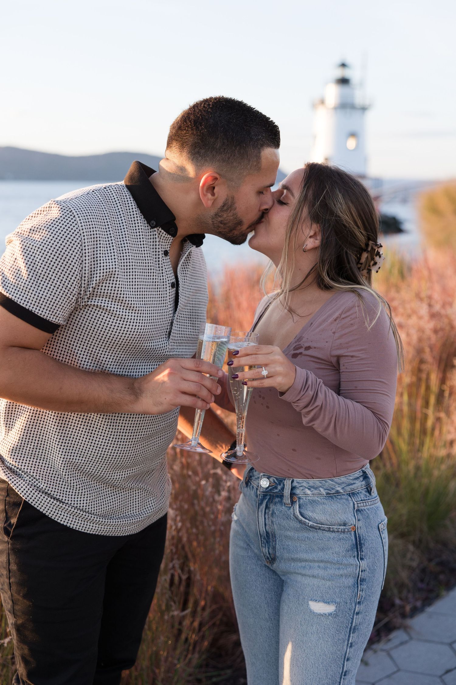 A romantic champagne toast and kiss shared by a couple at sunset.