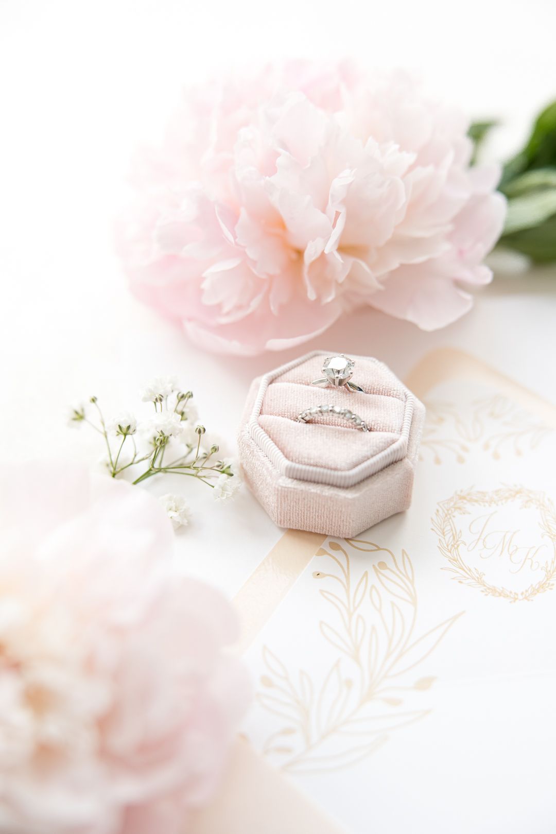 Delicate pink peony with wedding rings in velvet ring box and gold foil details.