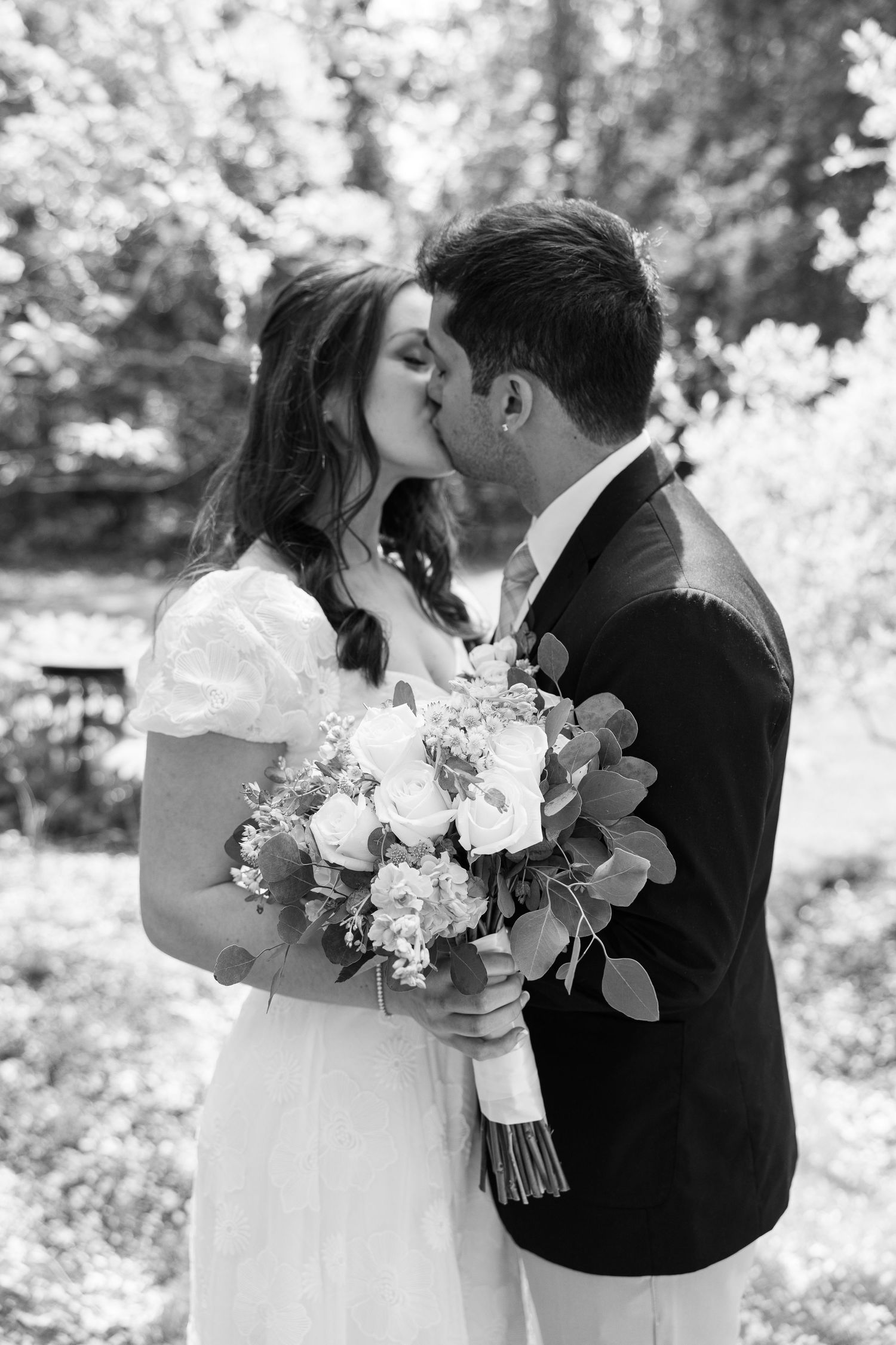 Romantic outdoor wedding moment with bouquet of white flowers.