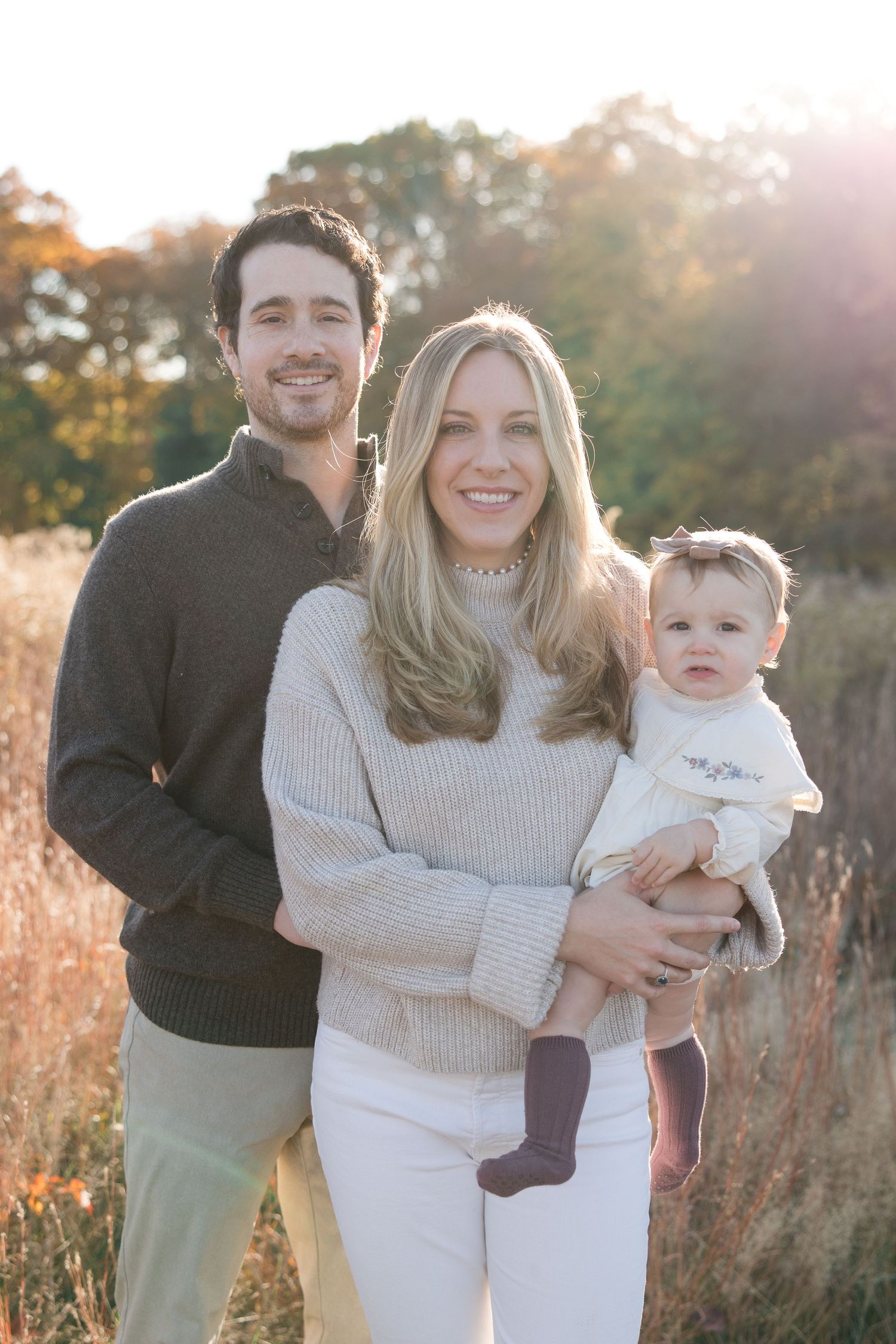 Family portrait in golden field with warm sunset lighting.