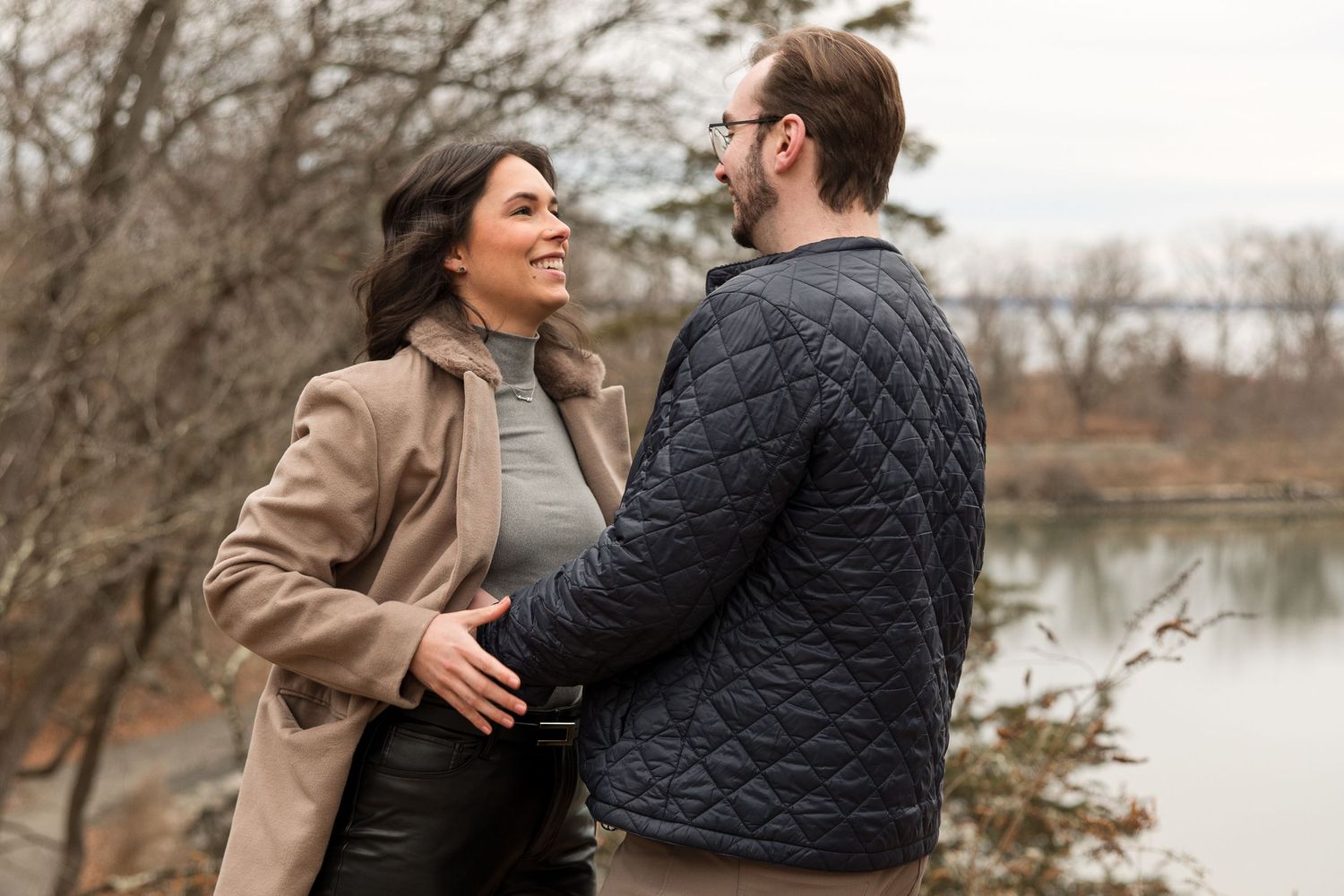 A joyful moment shared between two people in autumn outerwear by a lakeside.
