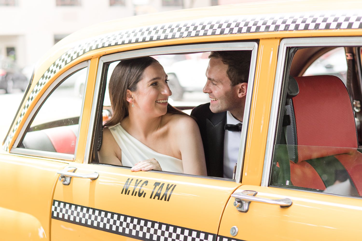 Happy newlyweds sharing a joyful moment inside a classic yellow NYC taxi cab.