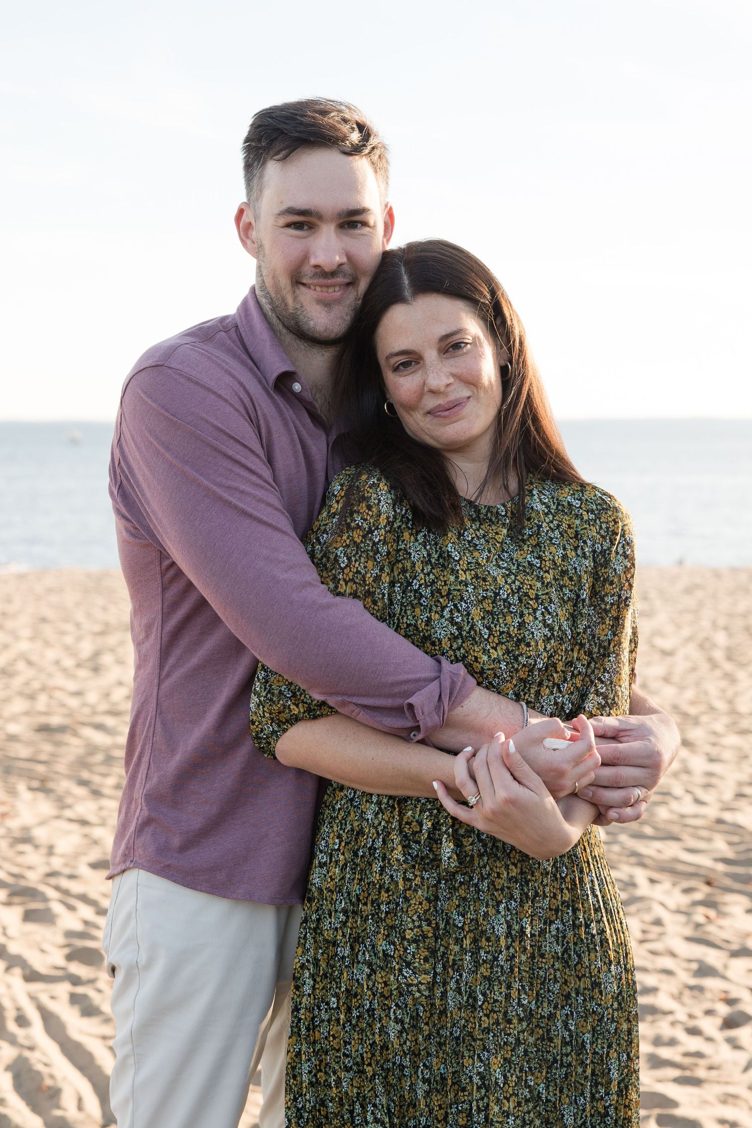 Romantic couple sharing an intimate moment on a beach with ocean in background.