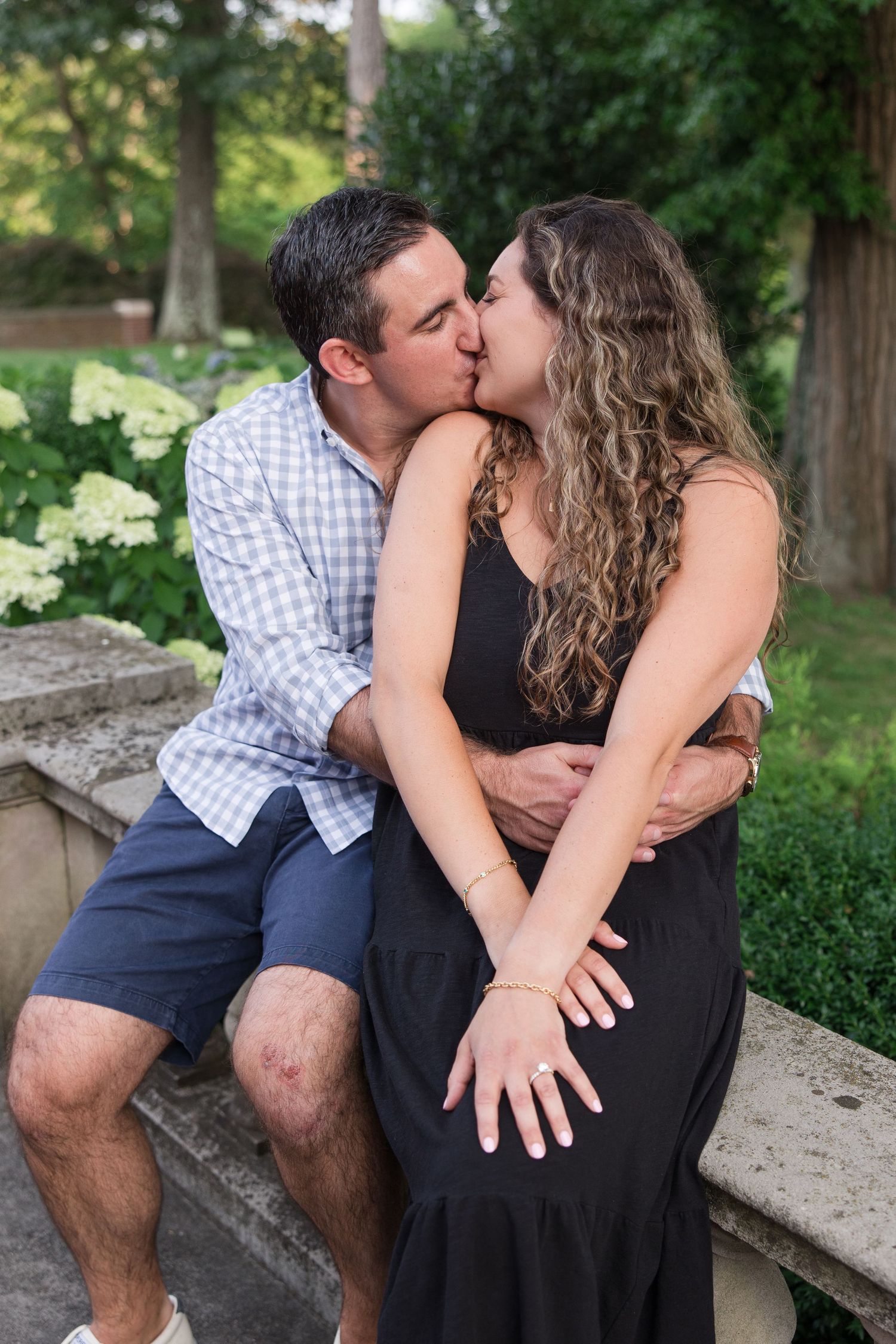 A romantic moment shared on stone steps surrounded by lush summer greenery.