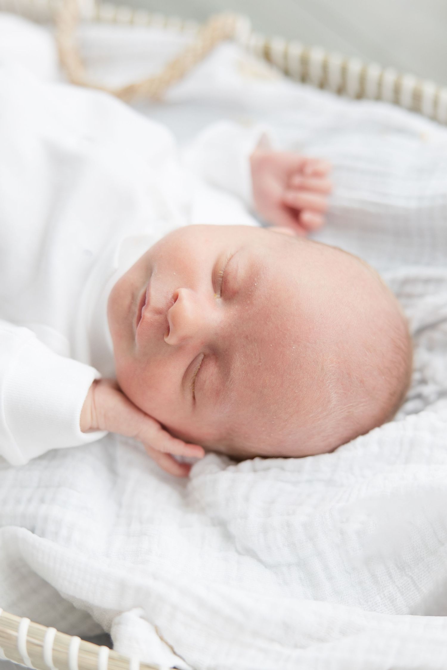 Harbor Point Newborn Photographer | Stamford Newborn Photography | A sleeping infant dressed in white rests on soft textured bedding.