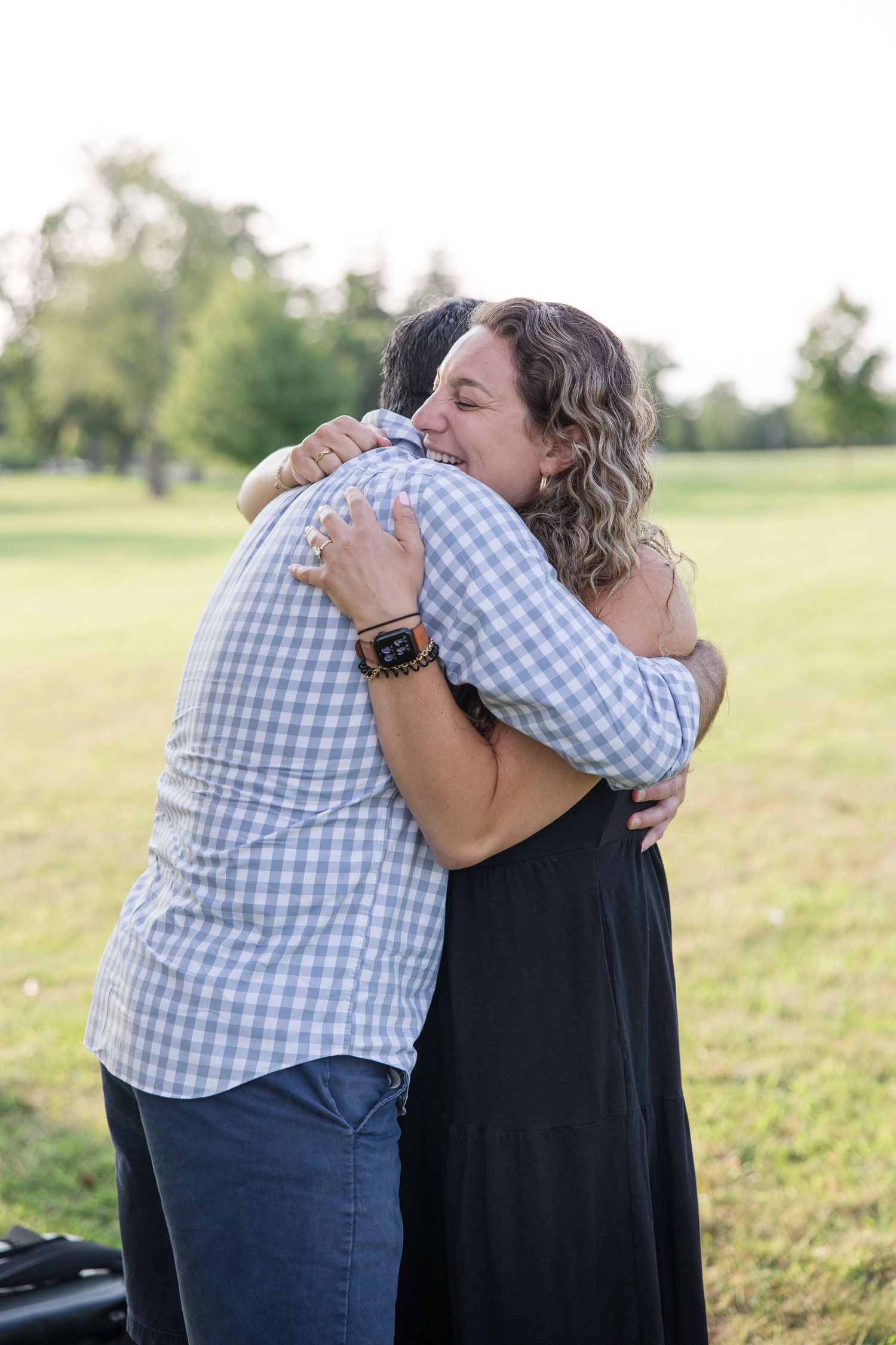 Two people sharing a warm embrace in a grassy field on a summer day.