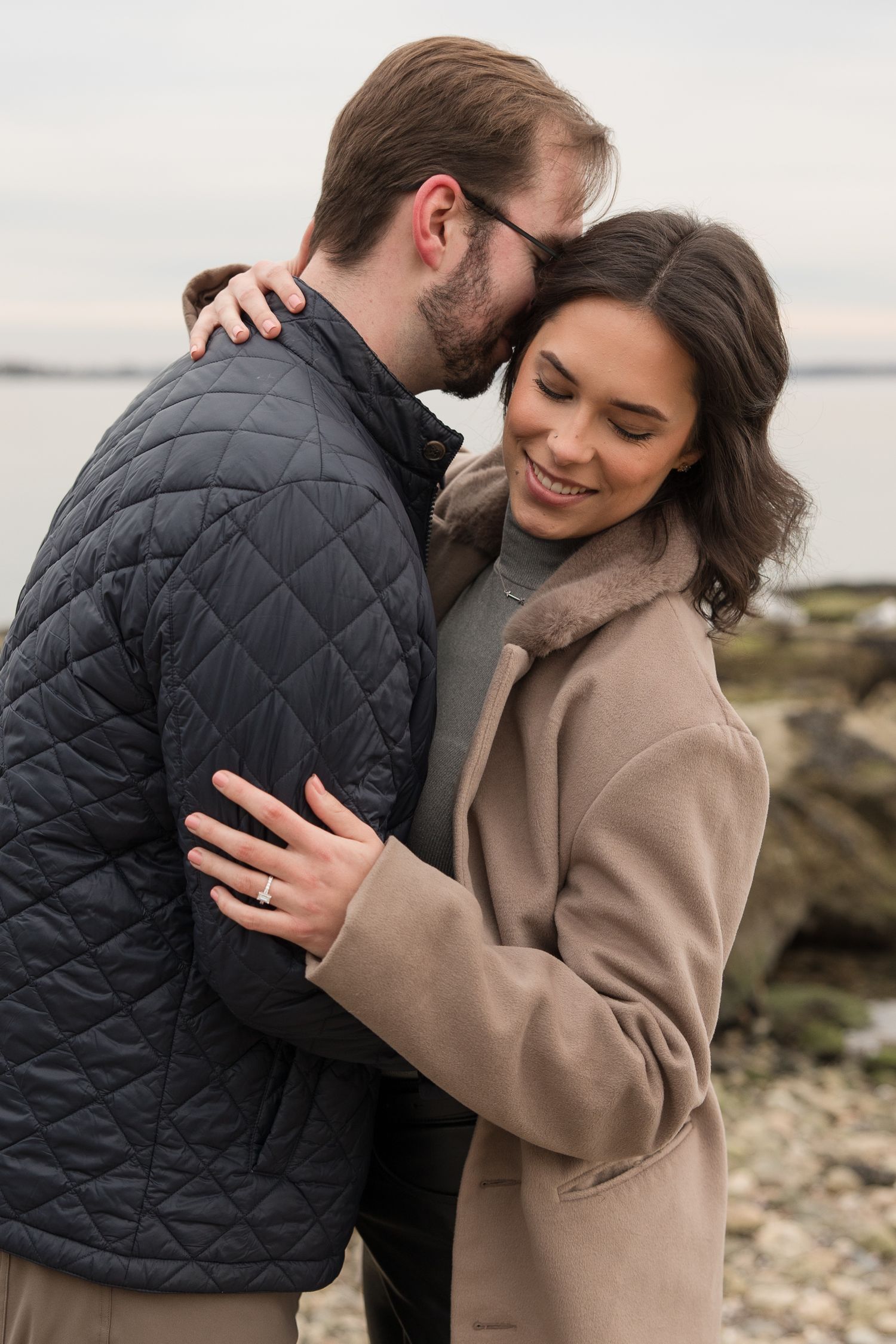 A couple sharing an intimate moment outdoors wearing contrasting winter coats.