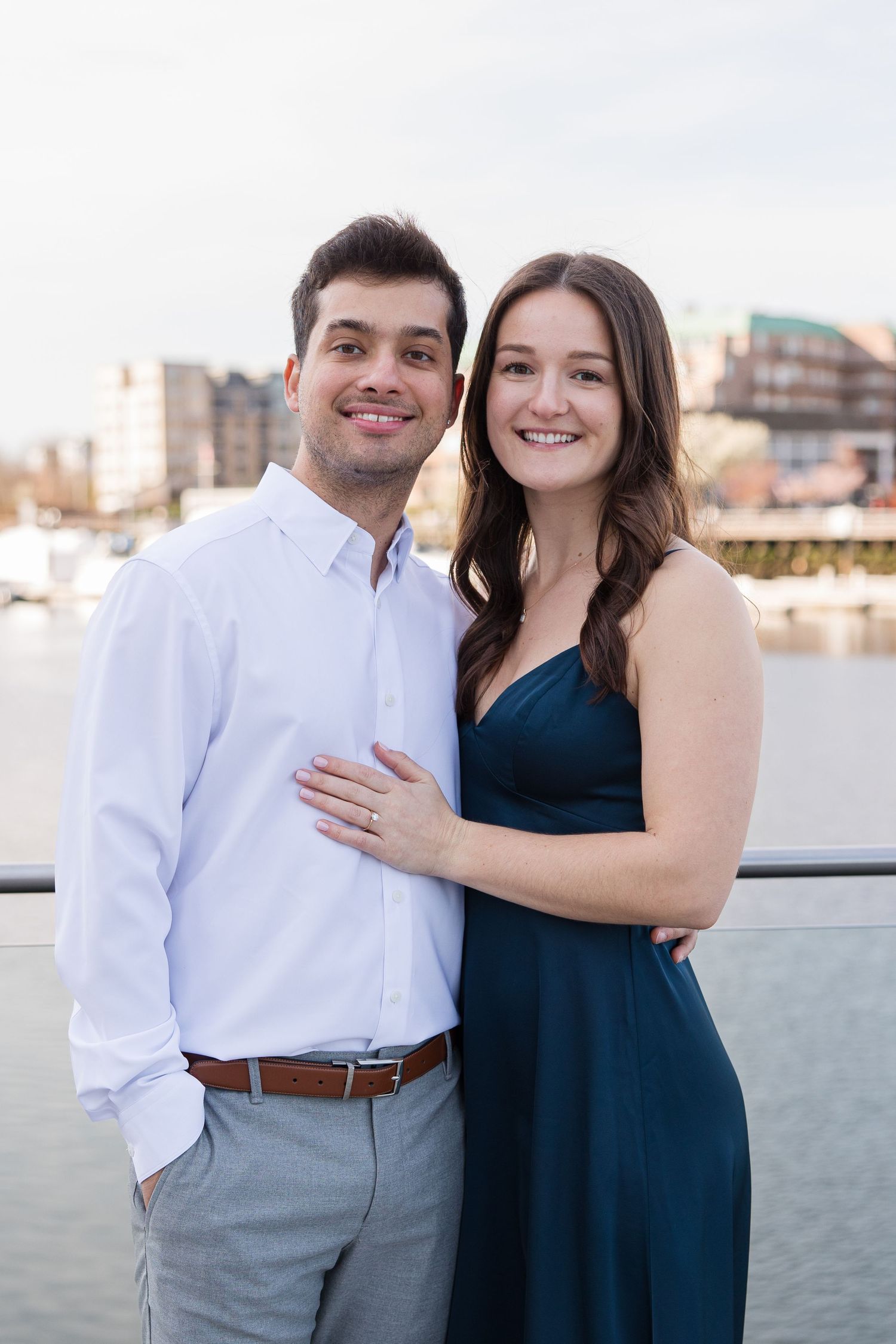 Couple sharing tender moment against waterfront backdrop during sunset.