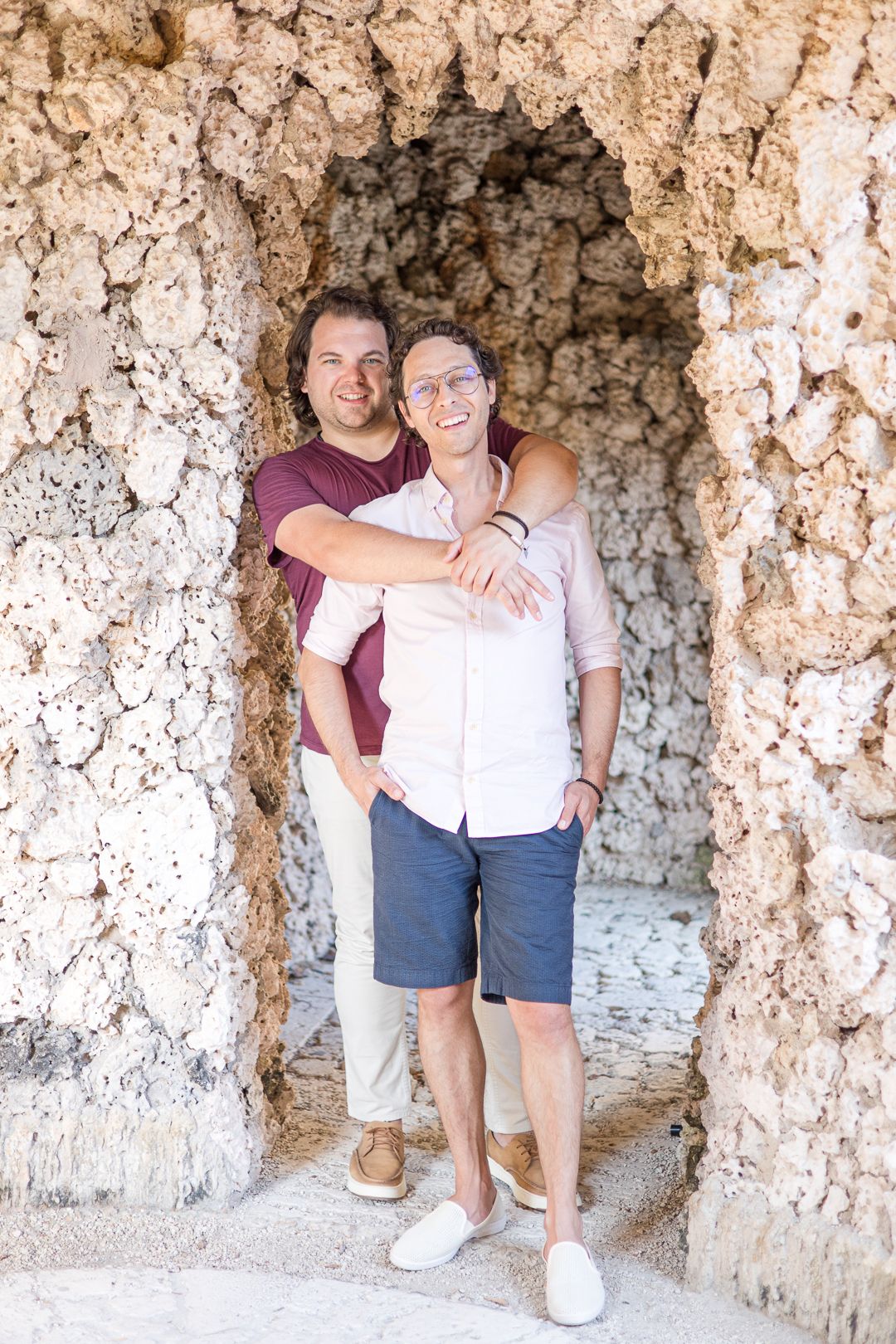 Two people embracing in a rustic stone archway.