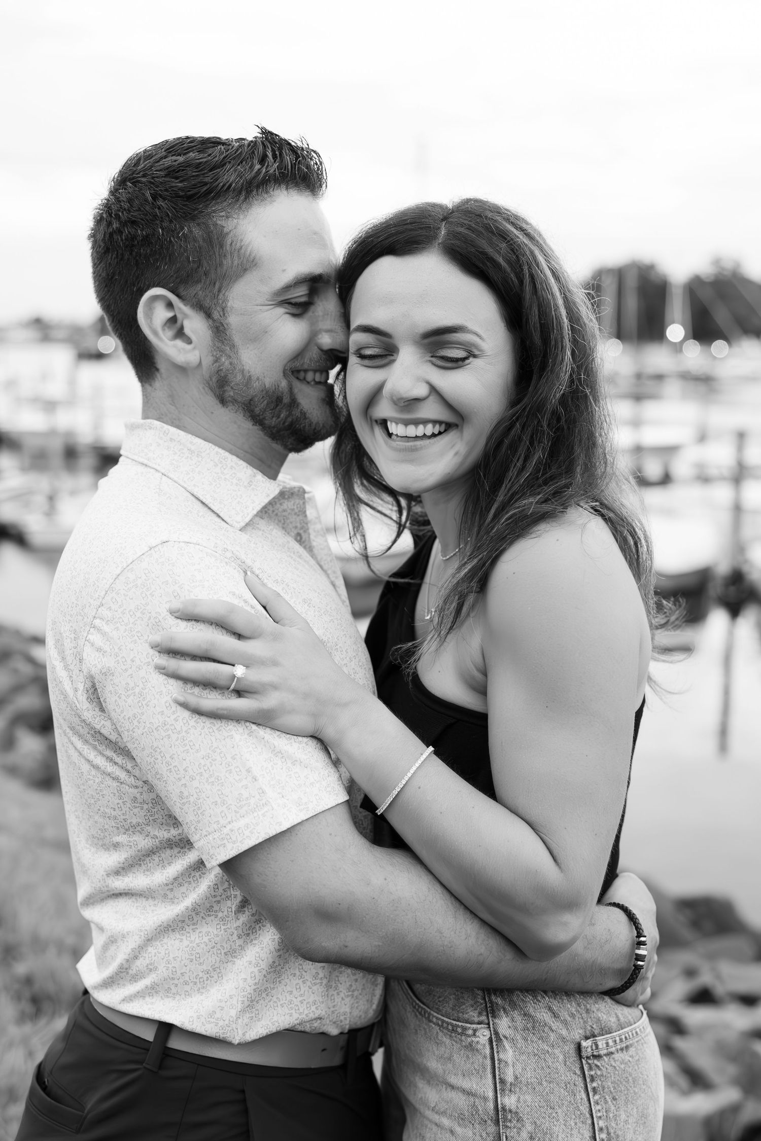 Black and white portrait of couple sharing intimate moment by waterfront.