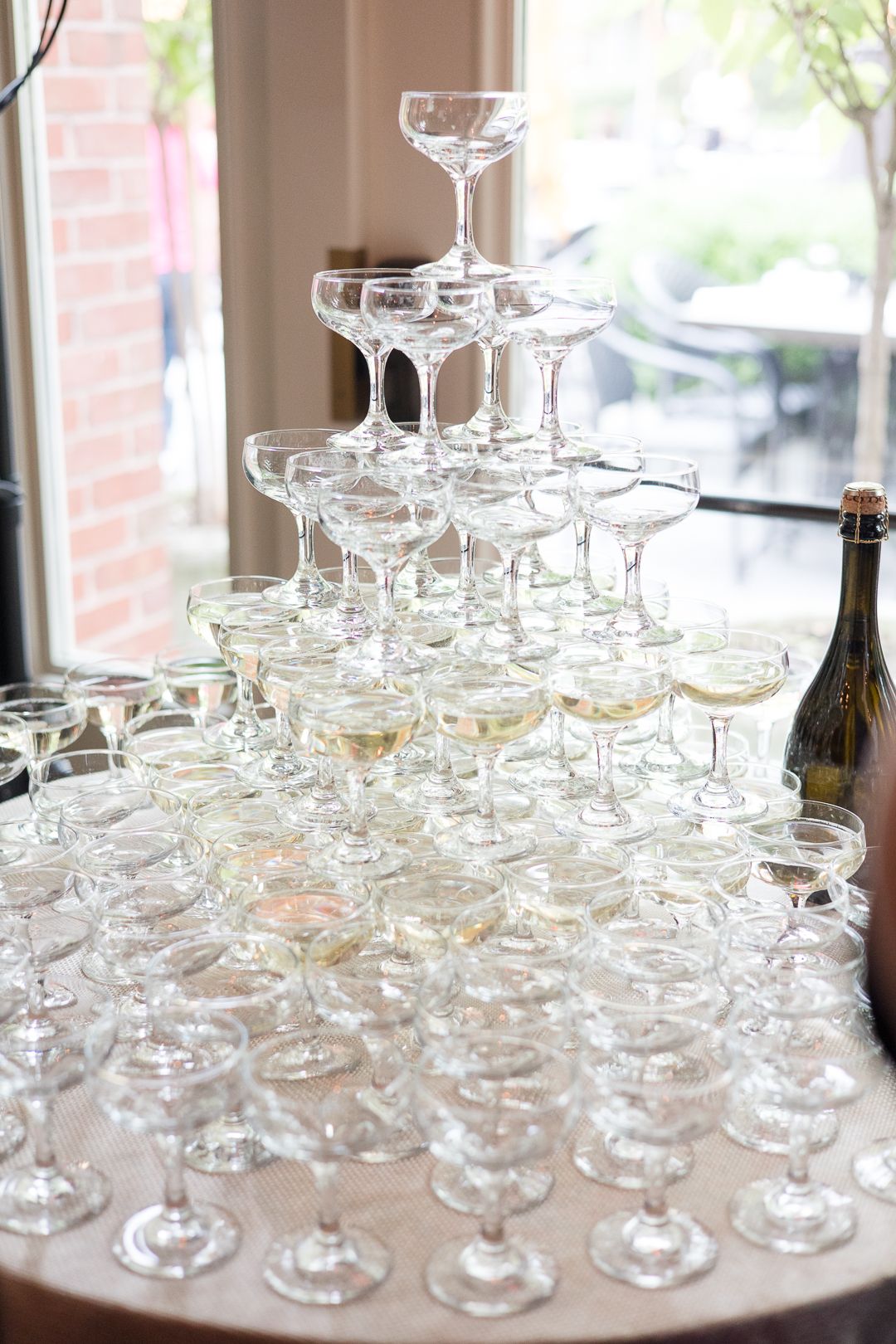 An elegant champagne tower display with multiple tiers of coupe glasses at a wedding reception.