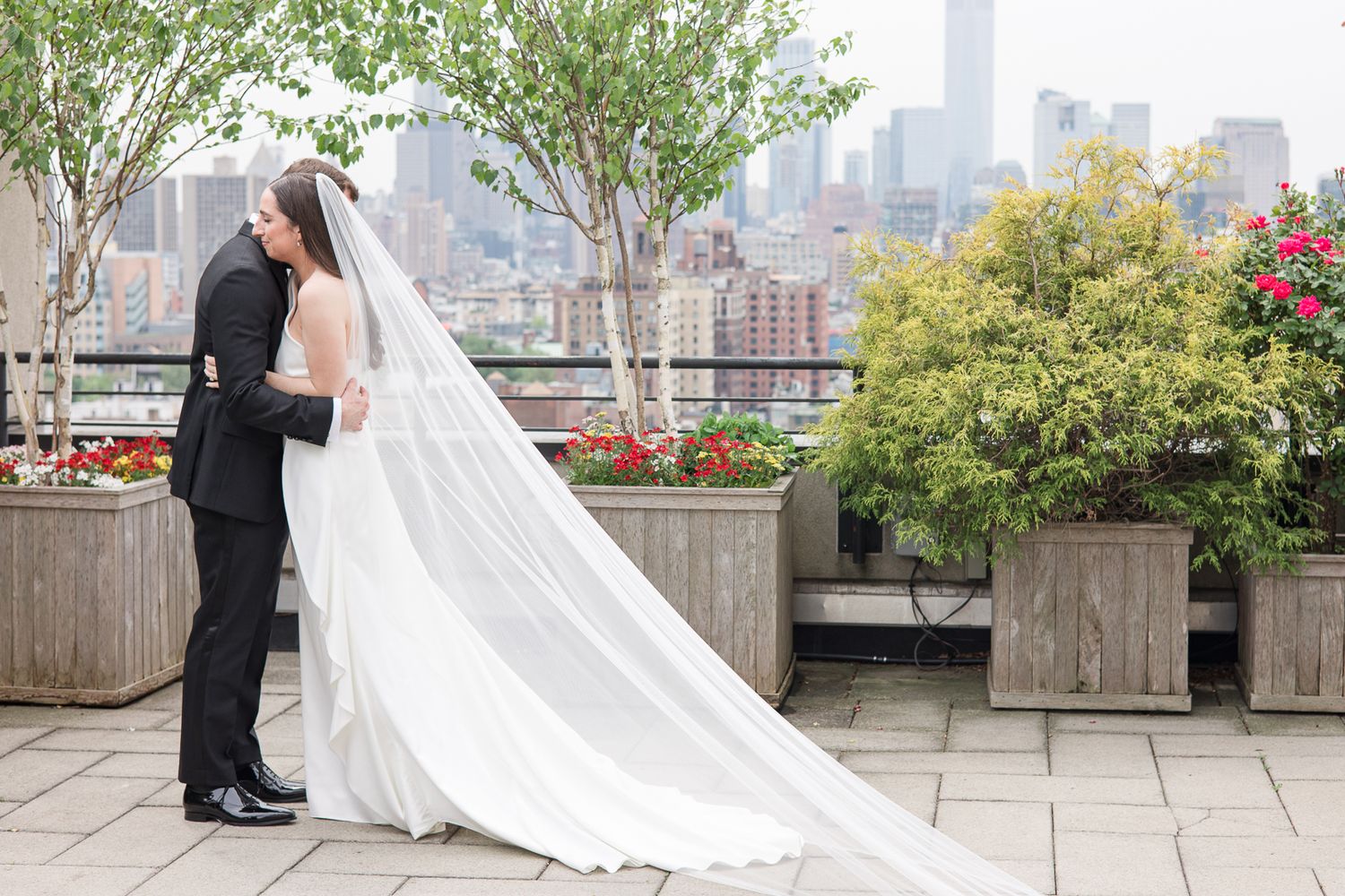 Wedding couple sharing an intimate moment on a rooftop garden with Manhattan skyline backdrop.