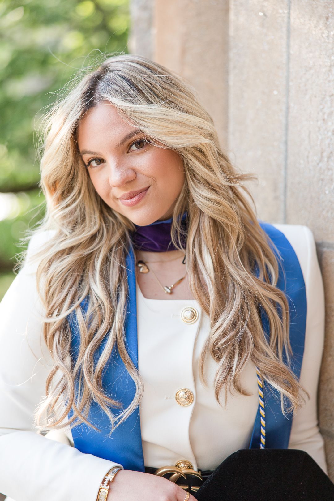 Close-up graduation portrait showing regalia details and purple accent scarf.