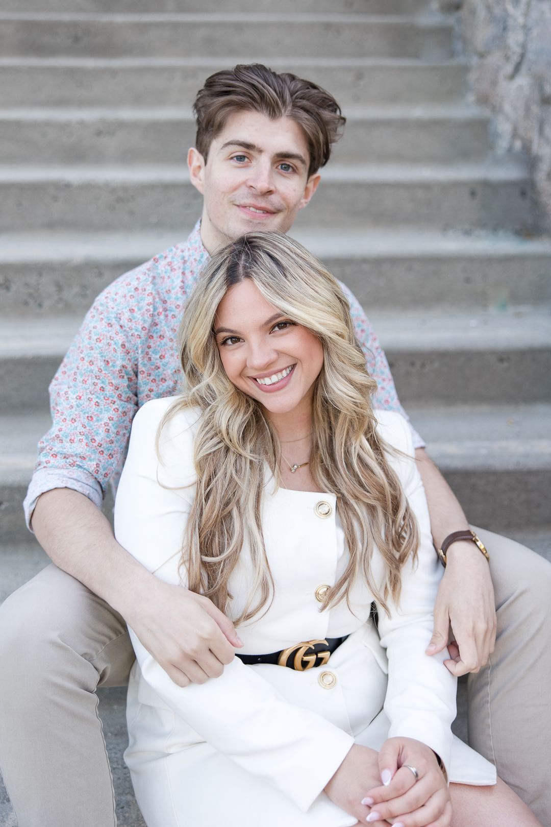 A couple sitting together on concrete steps sharing an intimate moment in coordinated casual attire.