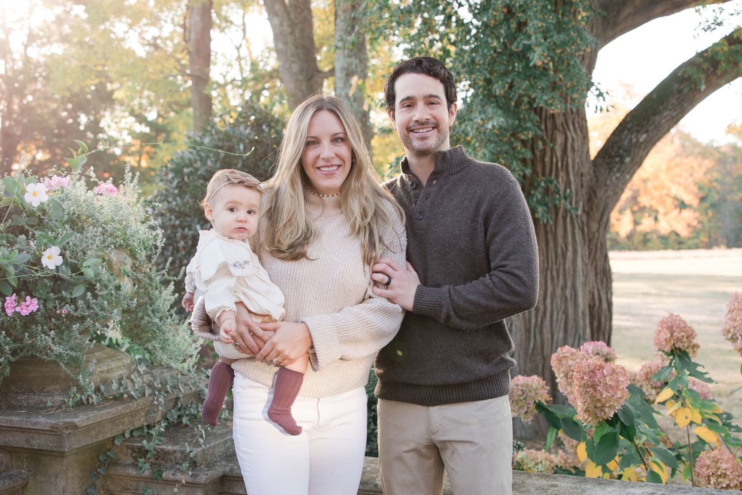 Family poses together in garden setting during golden hour.