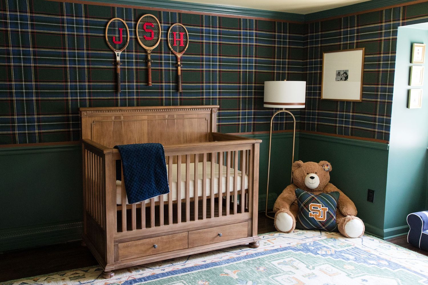 A rustic nursery with plaid wallpaper, wooden crib, and teddy bear in corner.
