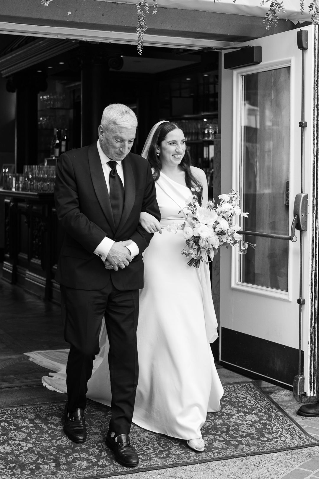 An elegant wedding entrance captured in black and white with a classic formal attire.