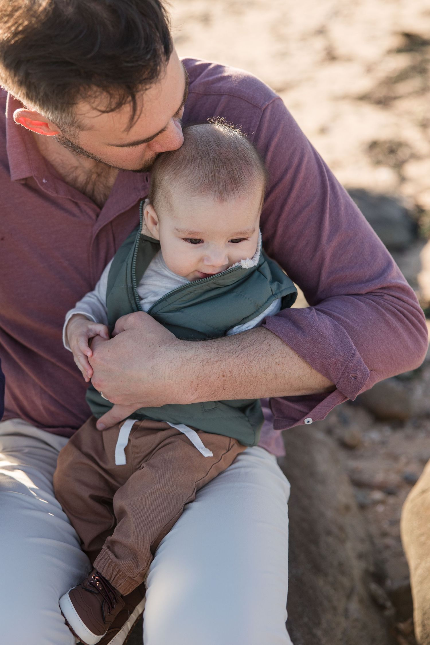 A tender moment between parent and baby on a sunny day outdoors.