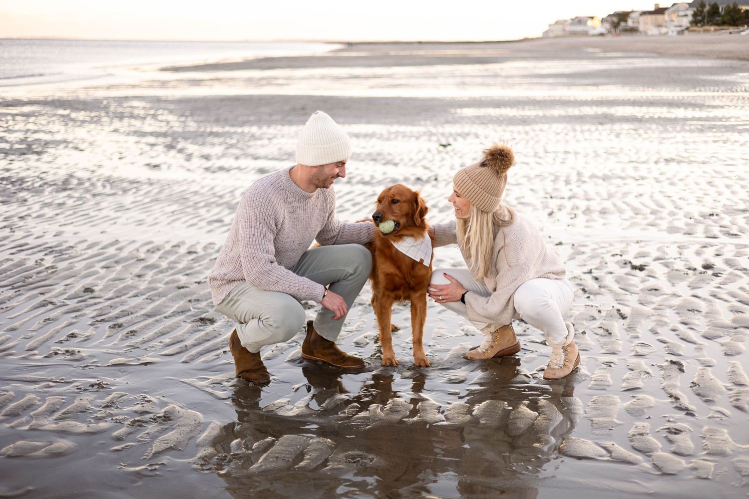 Golden retriever gets cuddles from companions at the beach shore.
