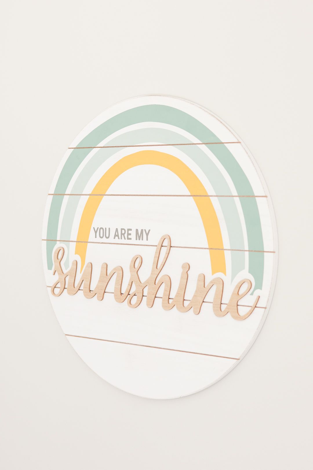 Decorative wall art featuring a mint green and yellow rainbow with 'You are my sunshine' text on white background.