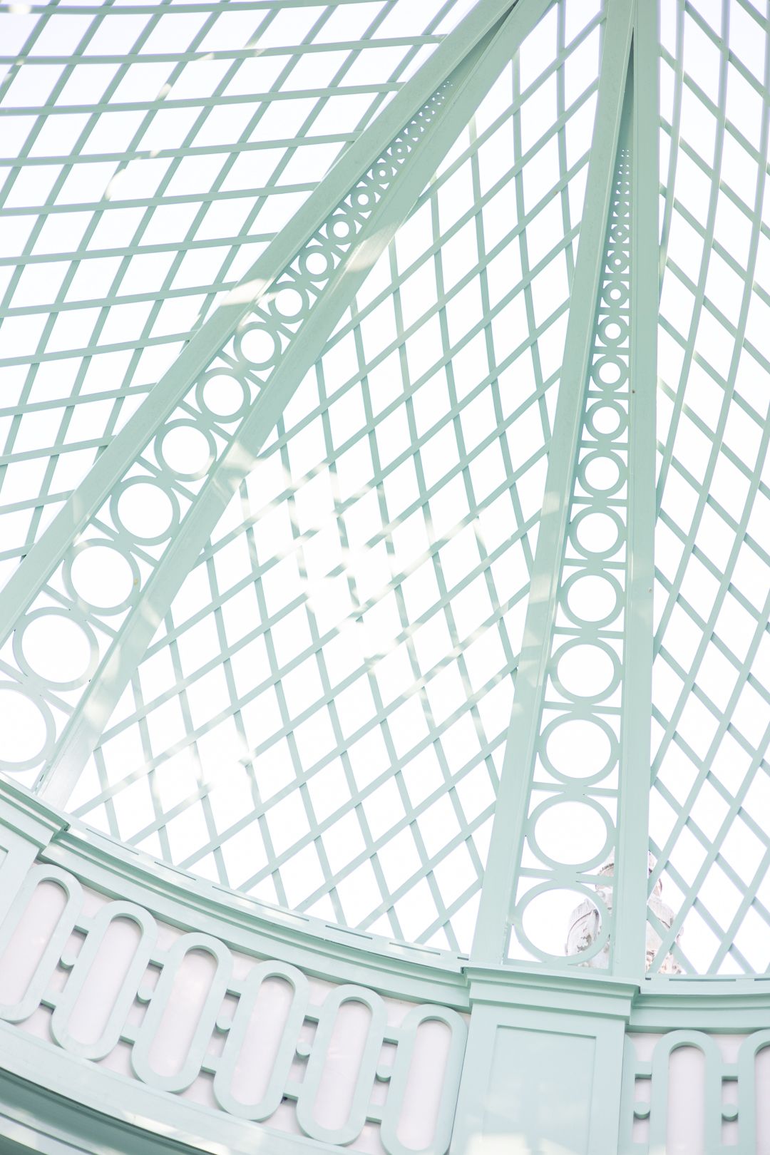 Architectural detail showing a mint green glass dome with geometric lattice patterns and decorative circles.
