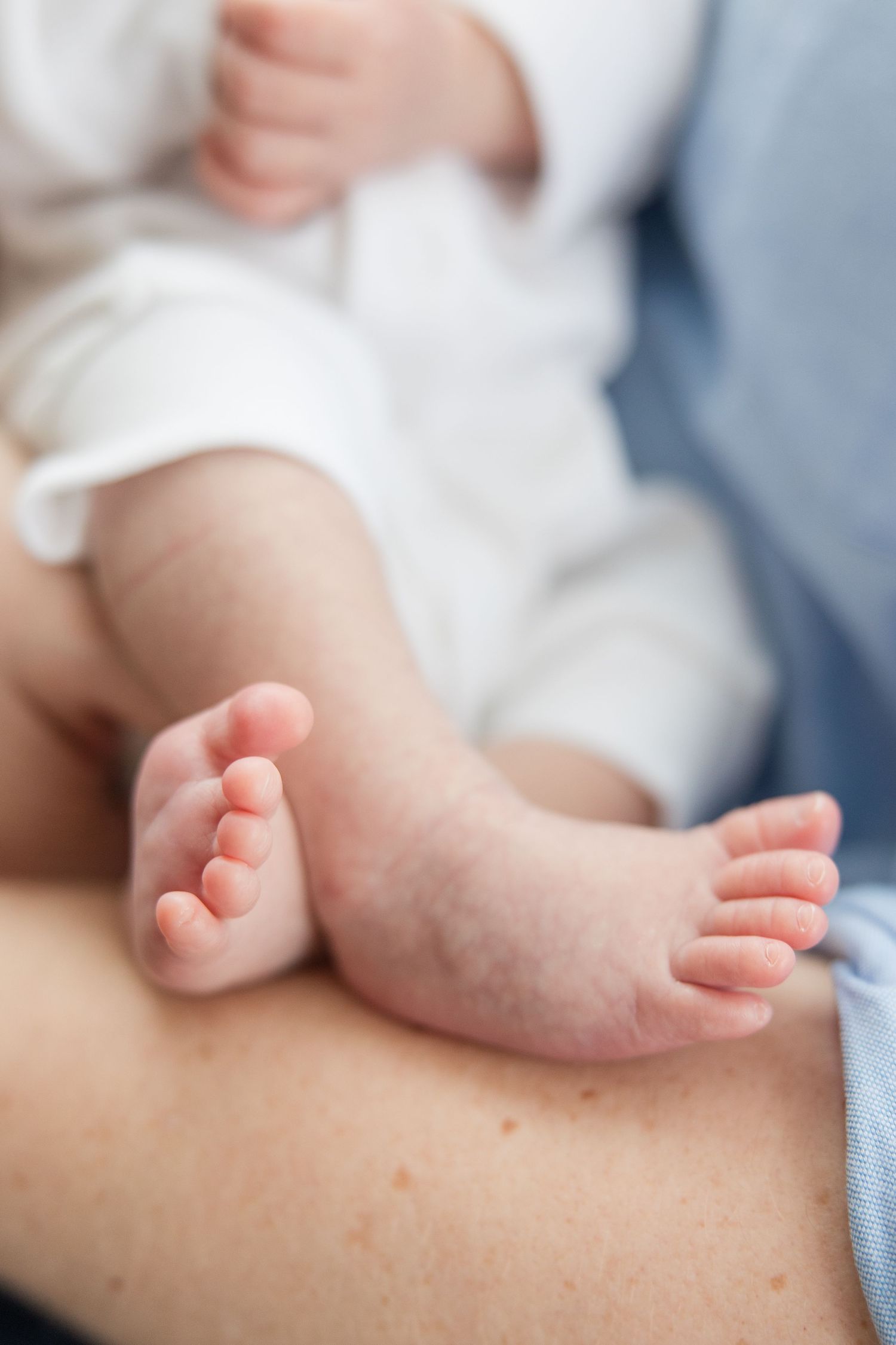 Close up of tiny baby feet resting on light fabric showing delicate toes and soft skin.