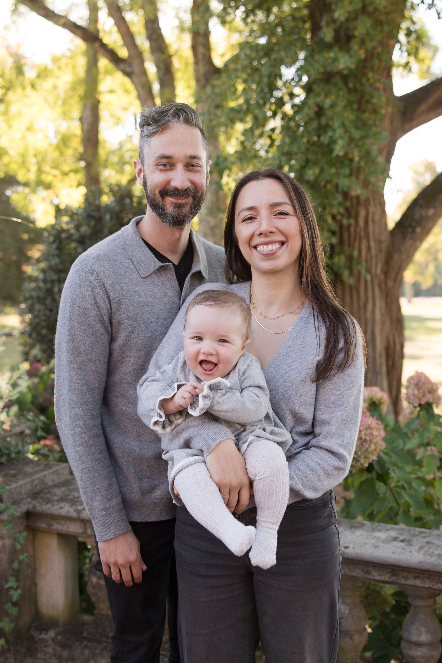 Happy family portrait taken outdoors in natural garden setting.