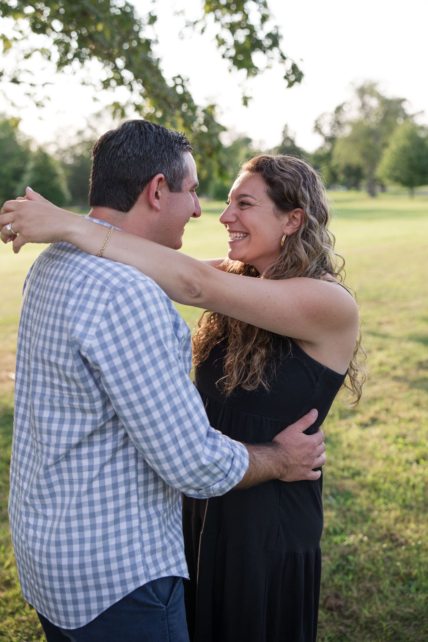 A joyful embrace shared between two people in a sunny park setting.