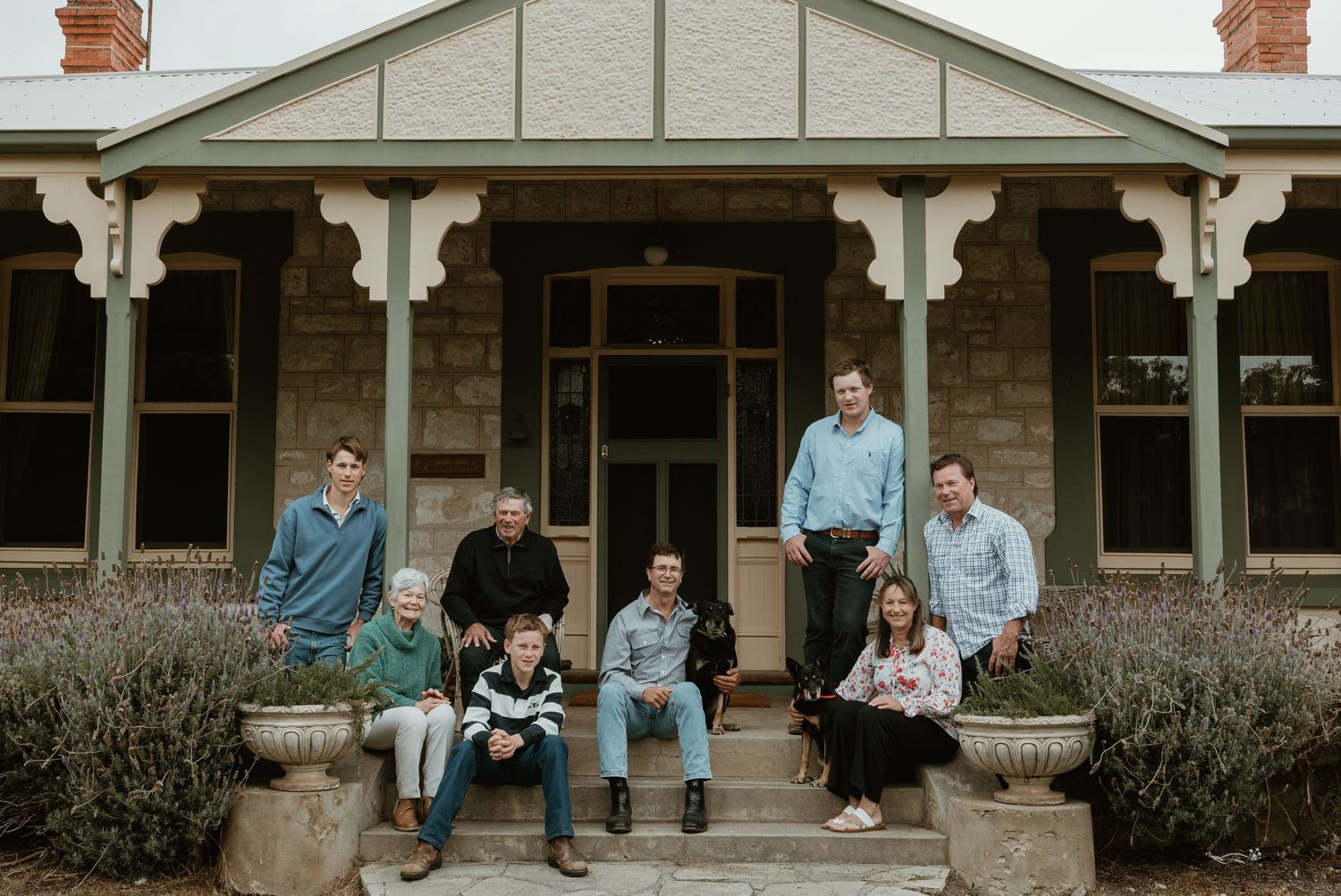 A casual family portrait on the front porch of a classic Australian heritage home.