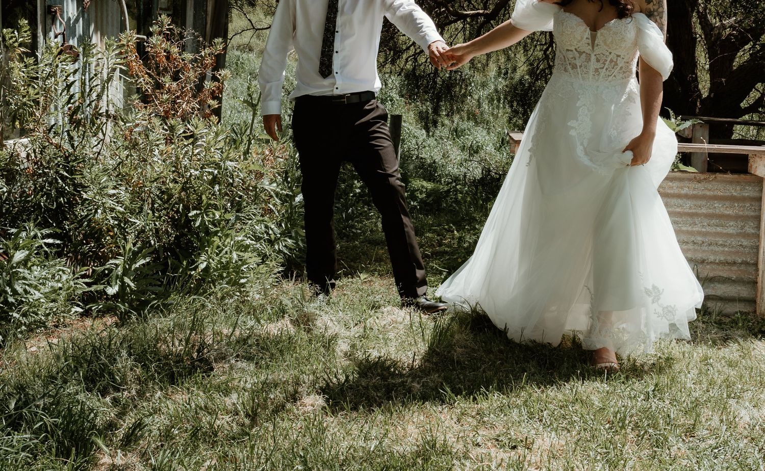 Couple dancing outdoors with focus on flowing white wedding dress and garden scenery.