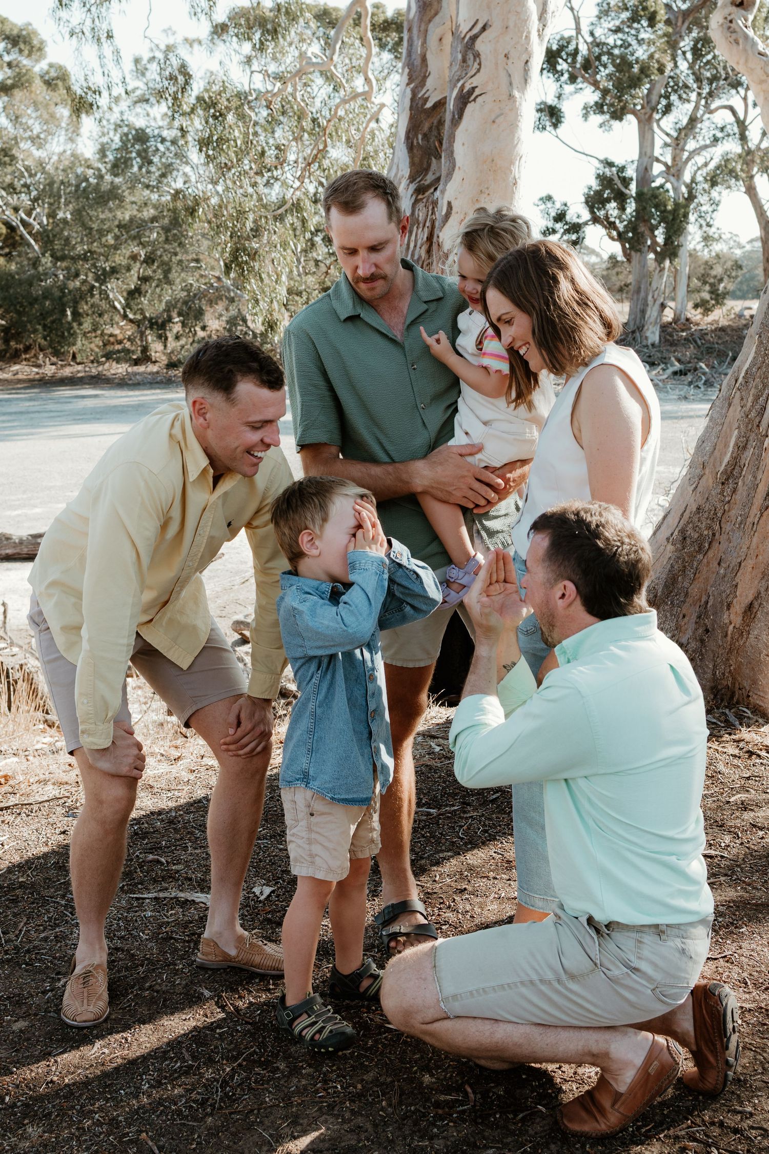 Group sharing joyful moment together under eucalyptus trees in natural outdoor setting.