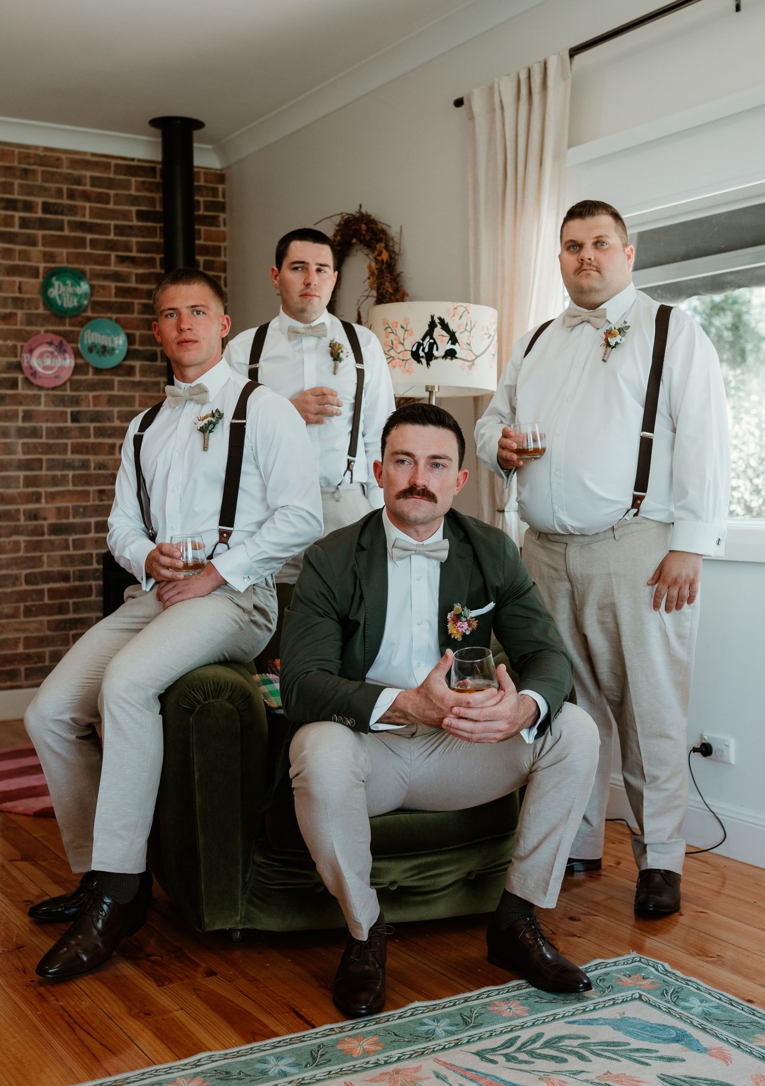 Groomsmen in white shirts and suspenders pose together in a rustic indoor setting.