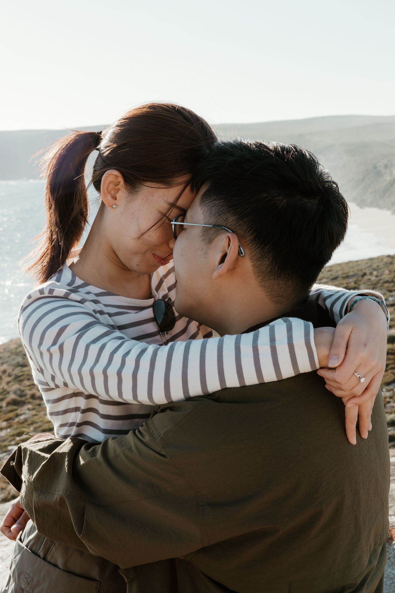 Couple embracing against coastal backdrop with ocean views. Kangaroo Island.