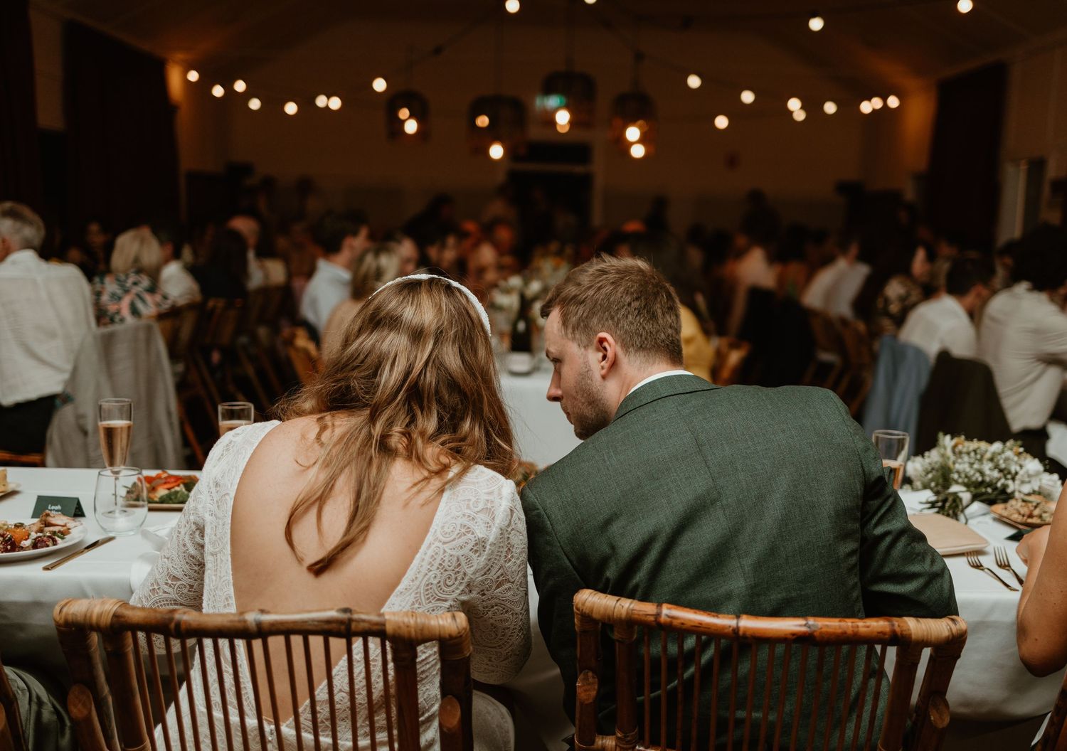 A couple shares an intimate moment at their wedding reception while seated at a decorated table.