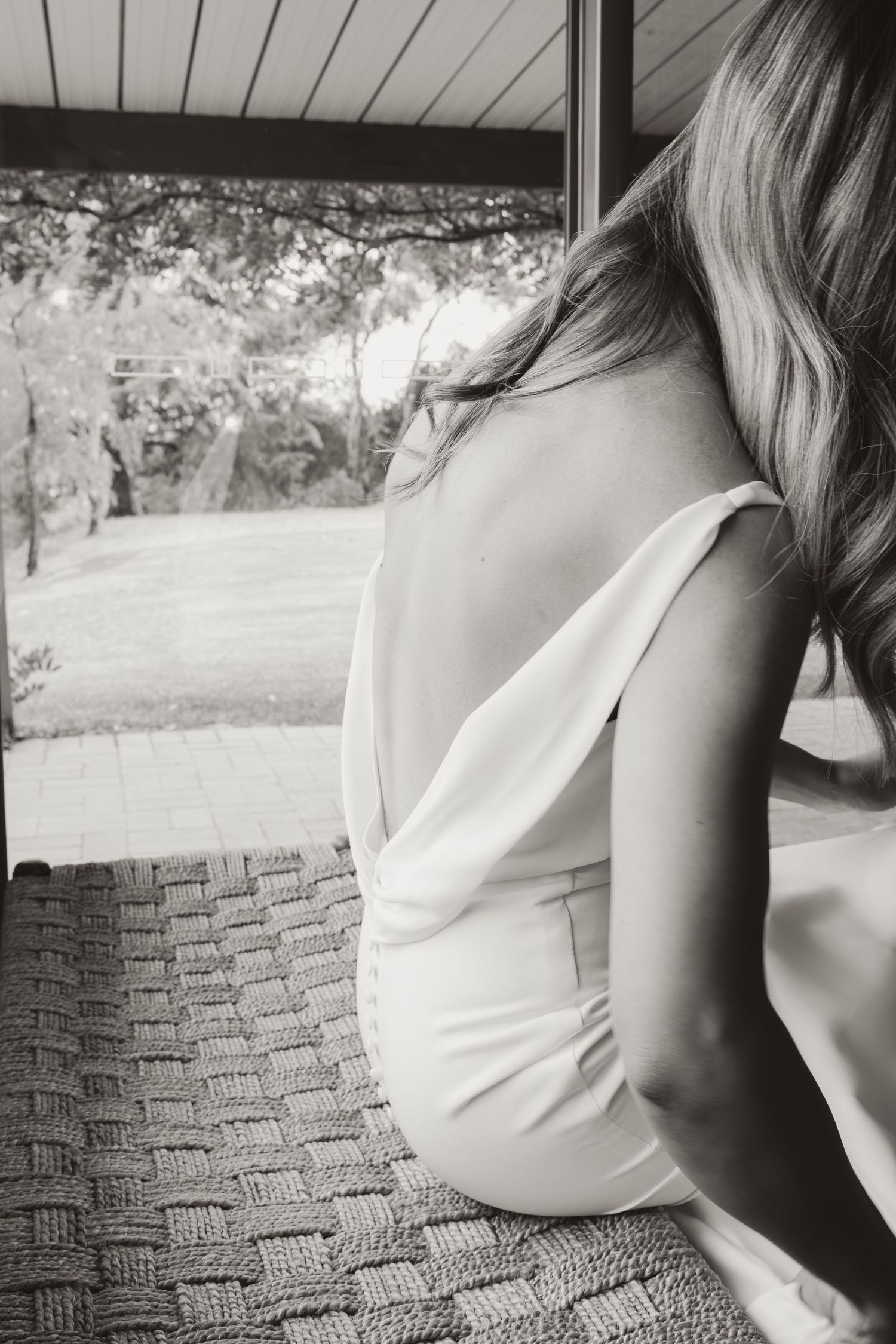 Close-up black and white photo of a wedding dress detail against a textured chair.