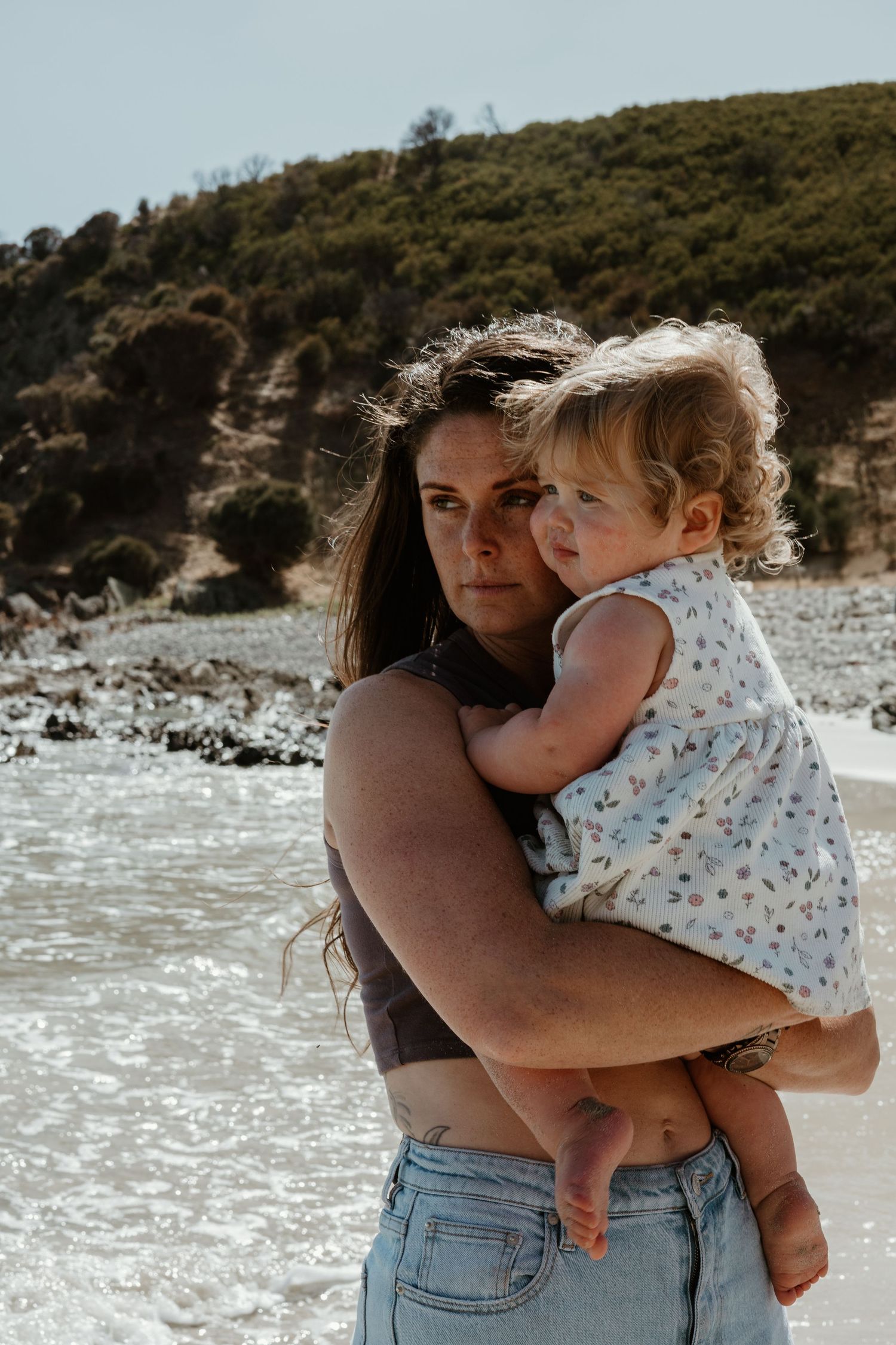 A tender embrace on a rocky beach with dramatic coastal cliffs in the background.